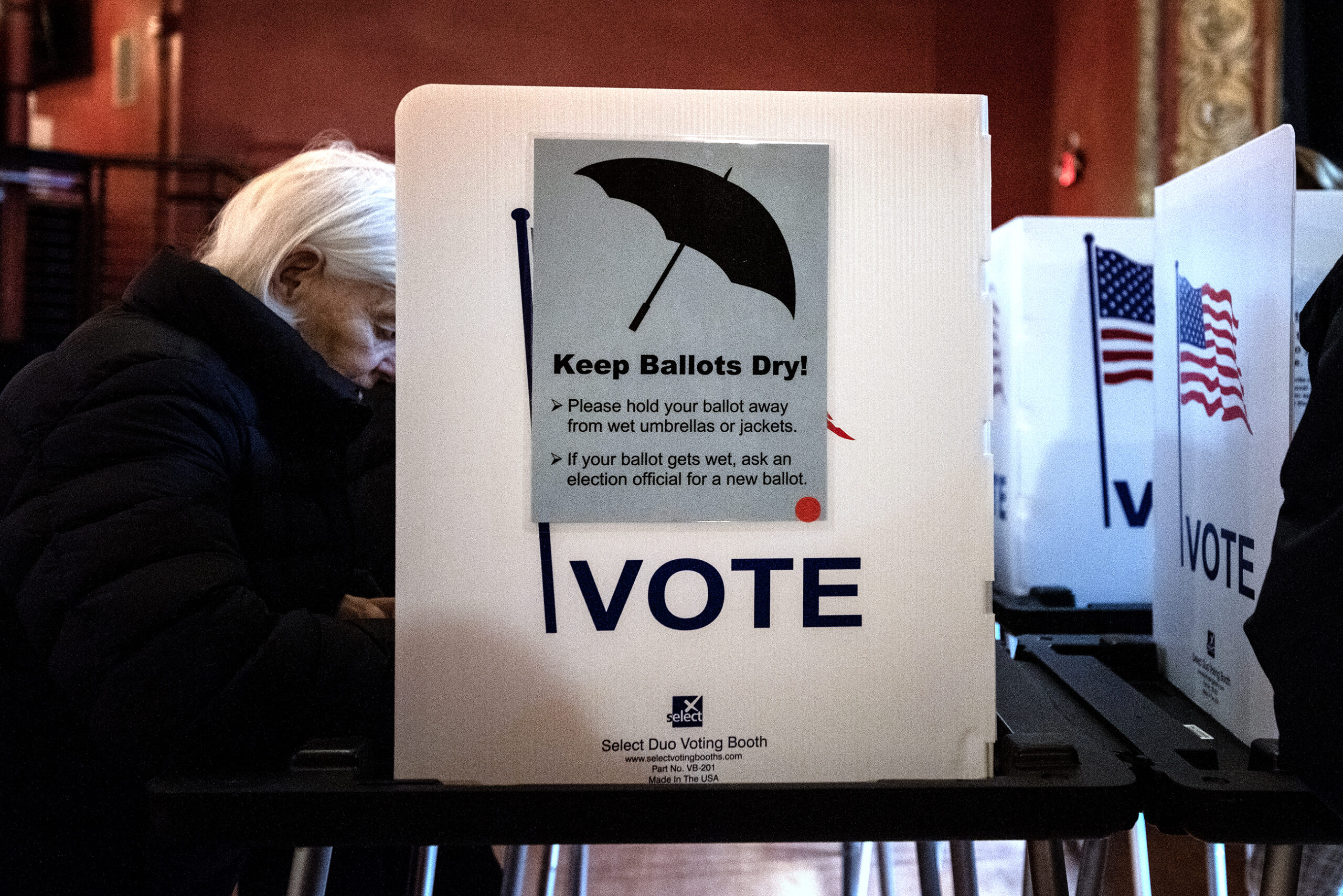 A sign on the side of a voting divider says "Keep Ballots Dry" and explains tips for not getting ballots wet due to the rainy weather.