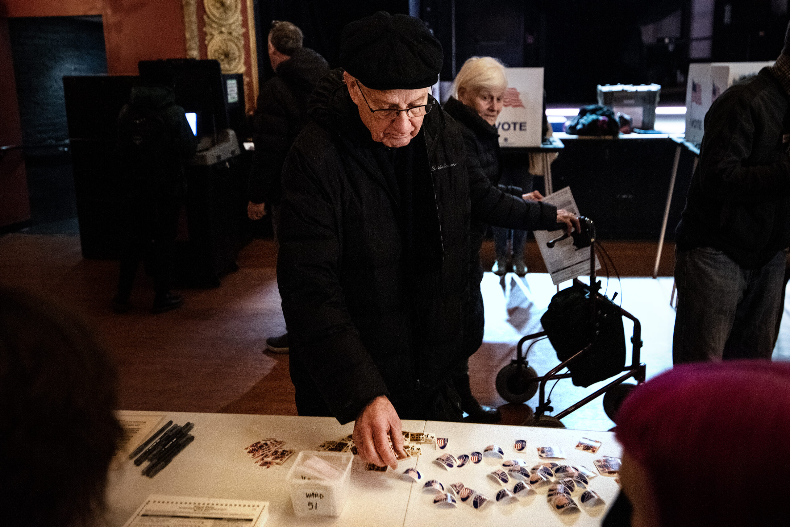 A man reaches down to grab a sticker from a table.