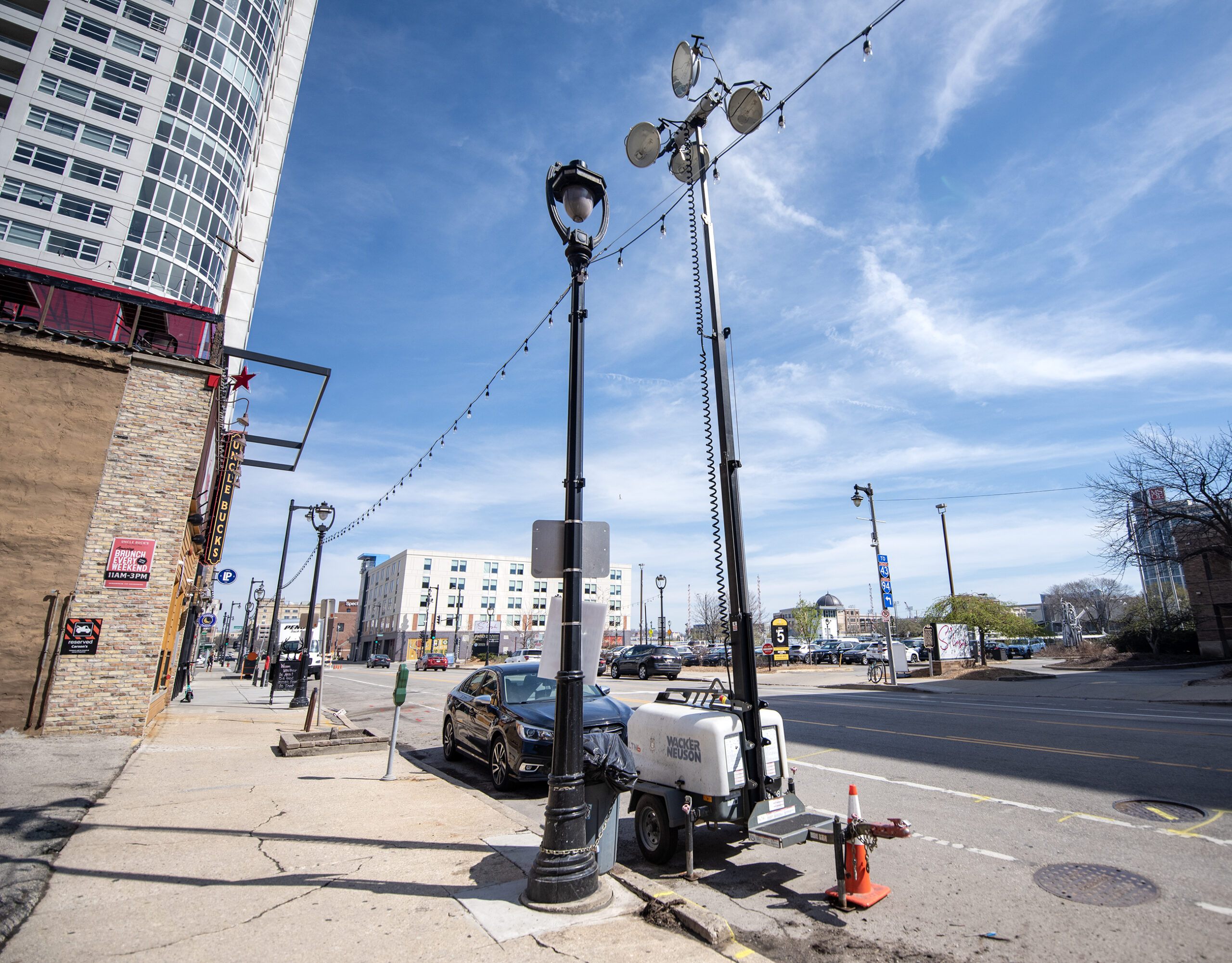 Lights atop a tall pole are set up next to a sidewalk.