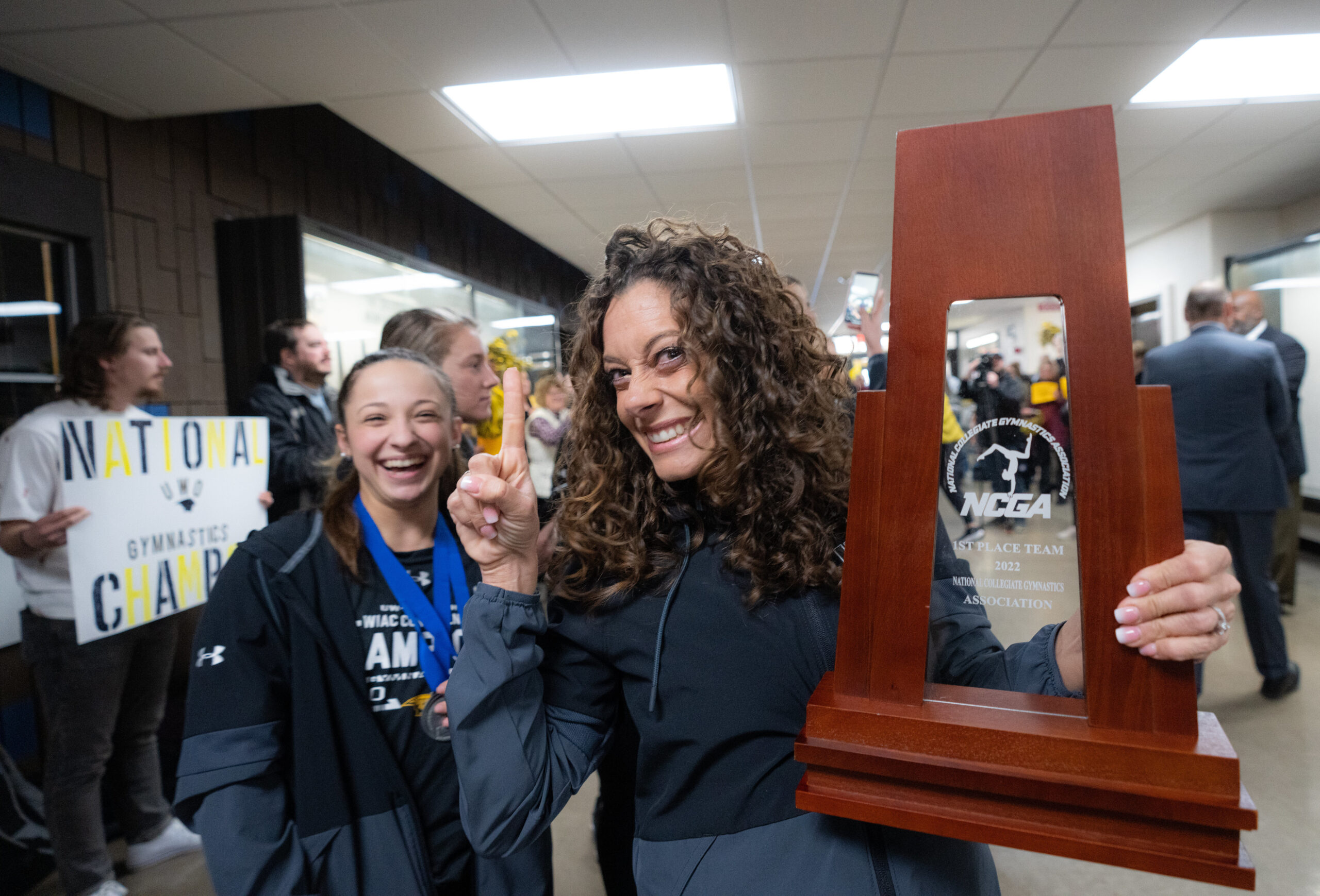 UW-Oshkosh gymnastics head coach holds the NCAA trophya