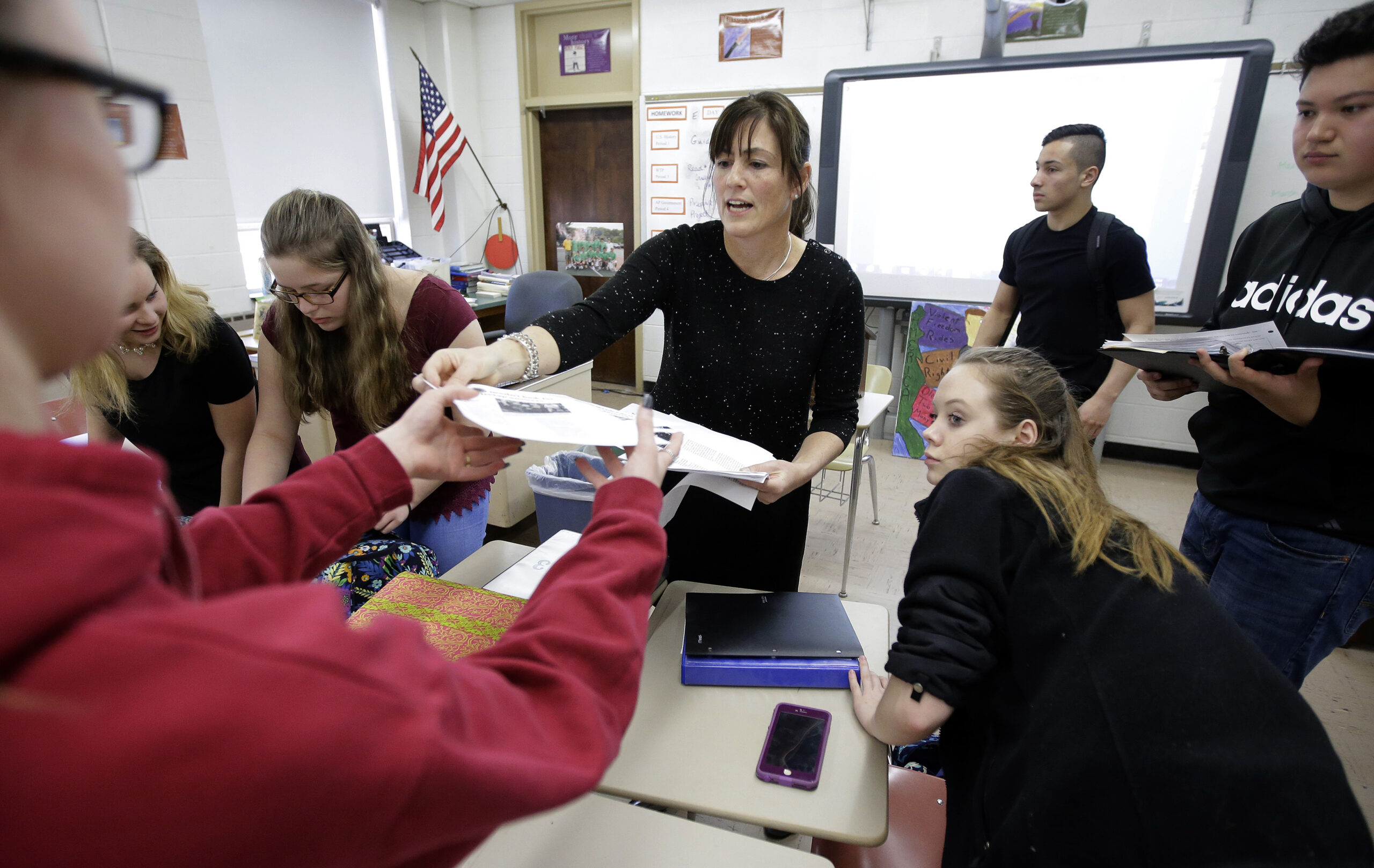 High school teacher Natalie O'Brien, center, hands out papers