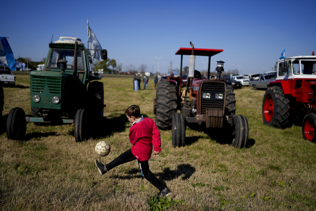 A child kick a ball during a protest in Gualeguaychu, Argentina, Wednesday, July 13, 2022. Argentina's main farm associations staged a 24-hour strike to protest against the economic policies of the government of President Alberto Fernandez, criticizing hi