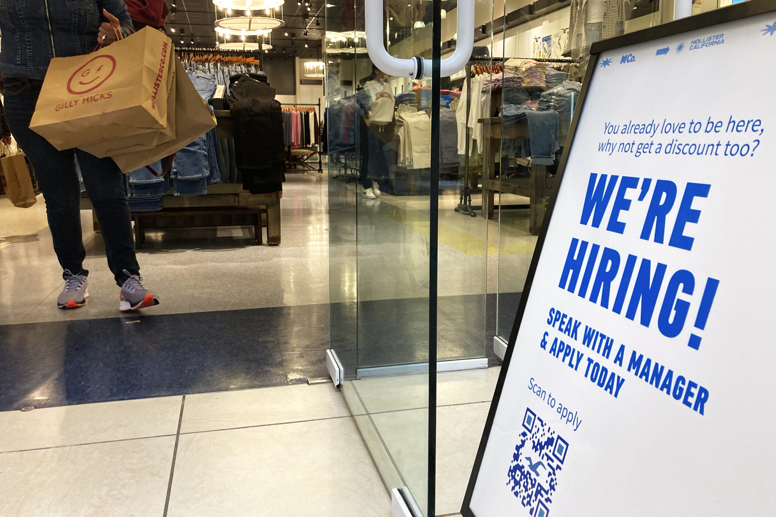 A "we're hiring" sign on display at a retail store.
