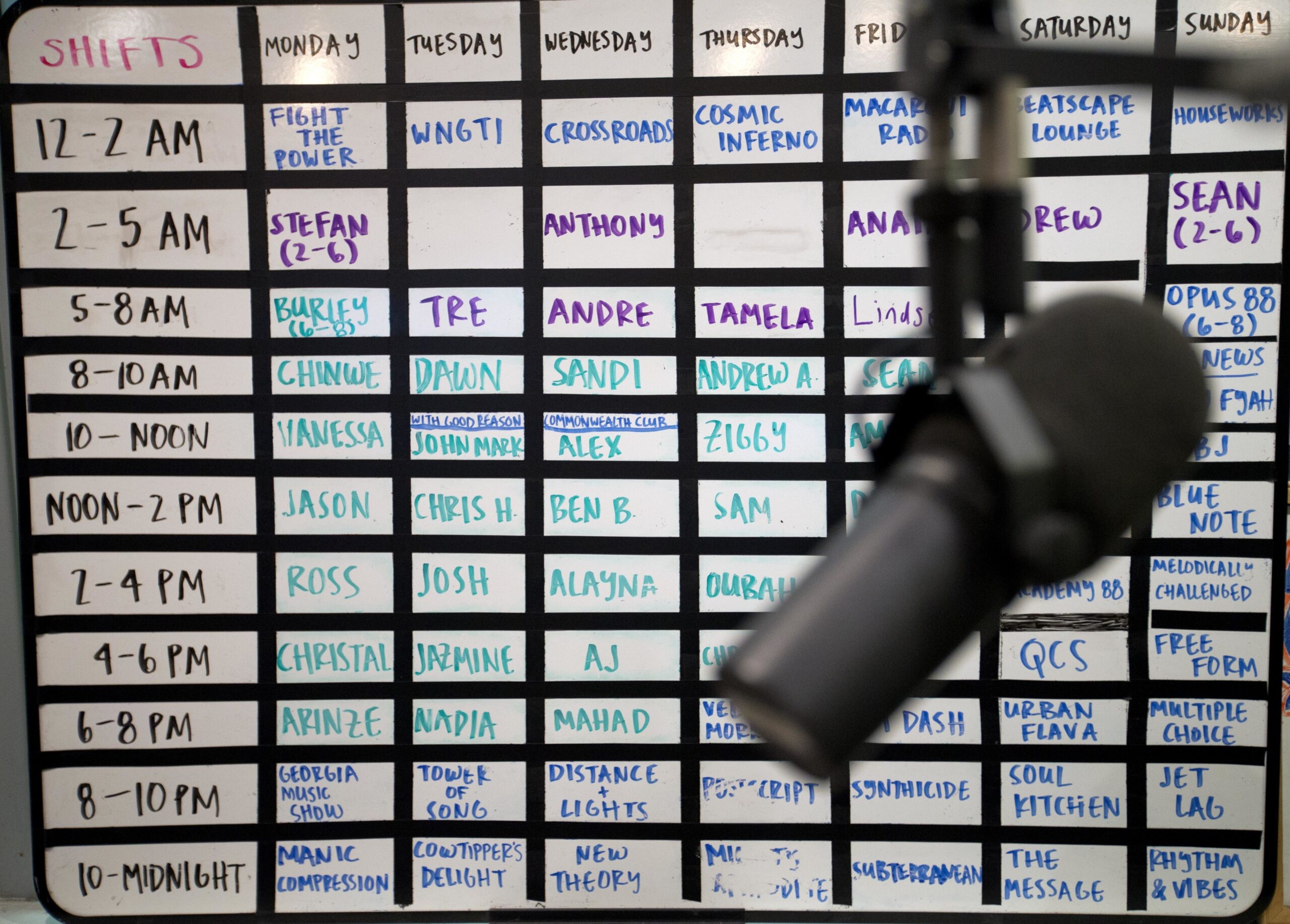 A radio microphone sits in front of a scheduling board
