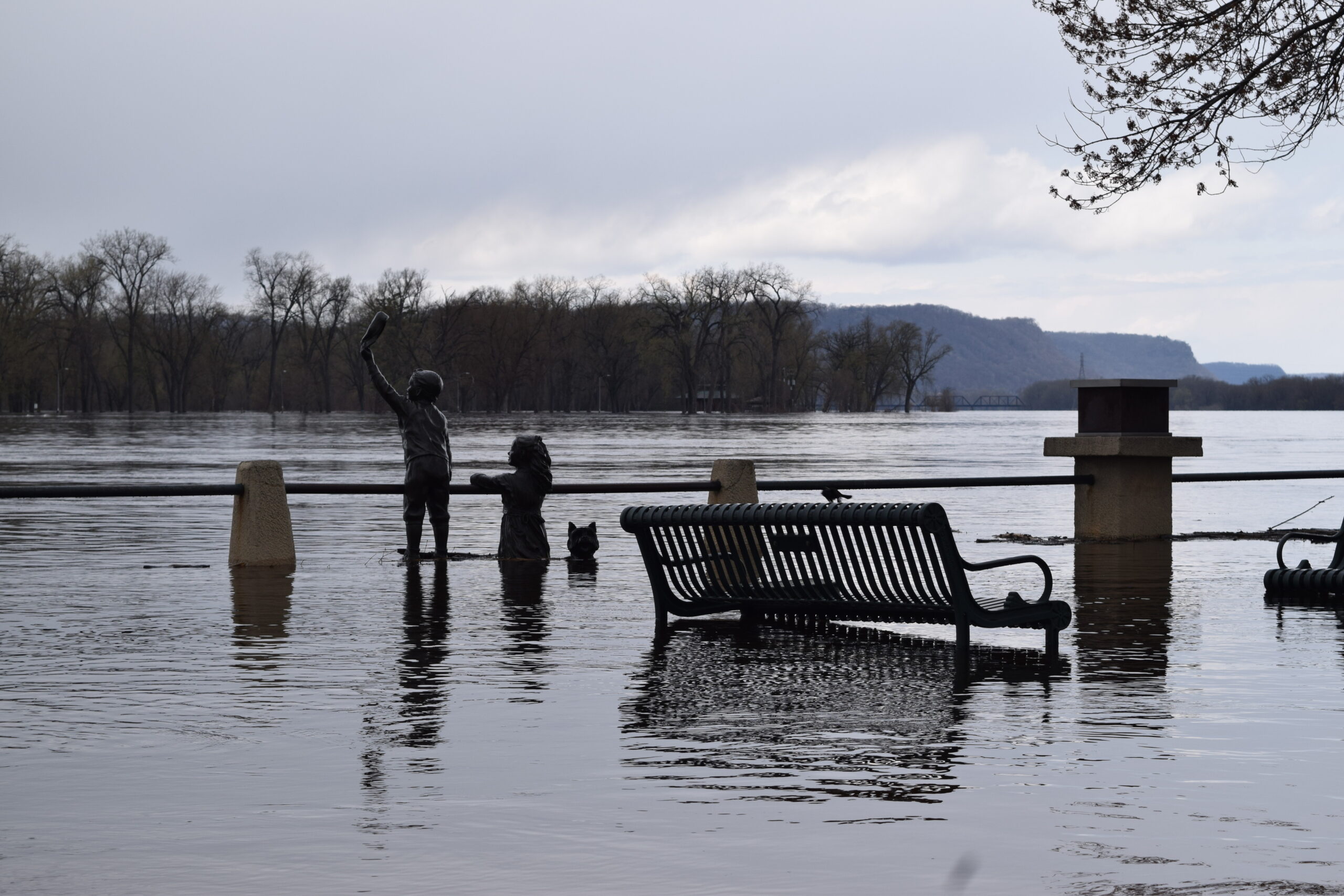 Floodwaters partially covers a statue of two children in La Crosse's Riverside Park