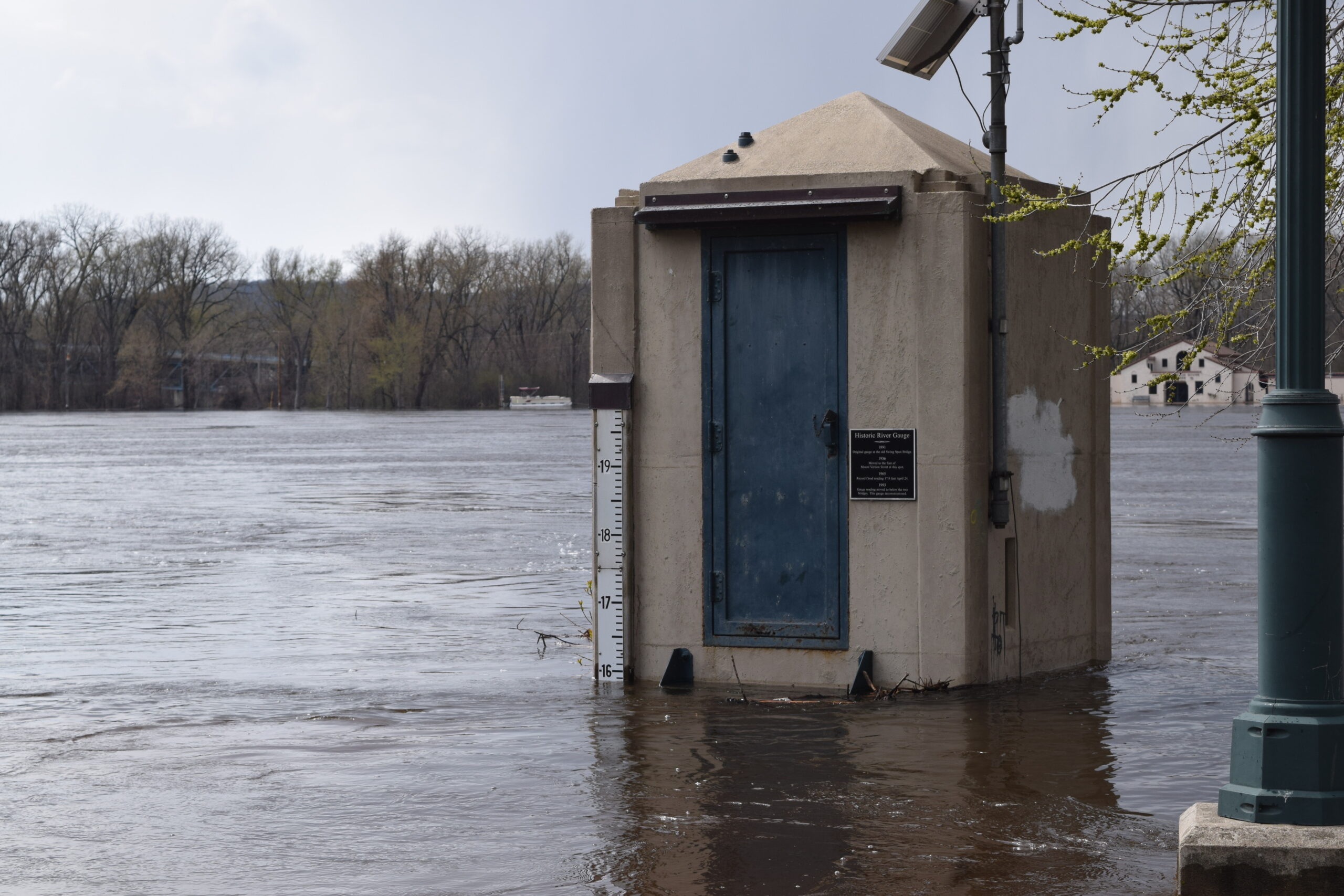 A river gauge shows floodwaters nearing 16 feet at a La Crosse park