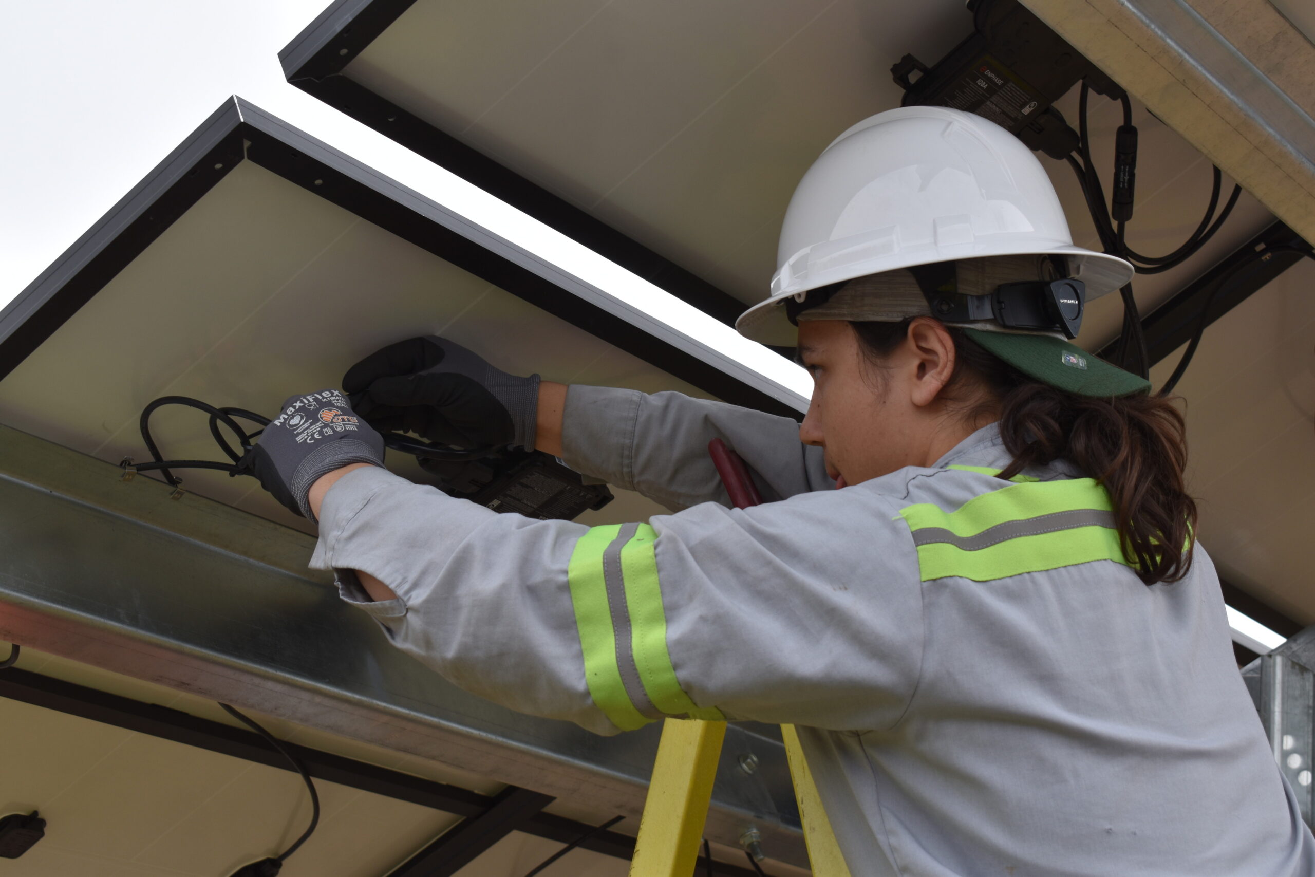 A member of the Menominee Nation works on the wiring under a solar panel on the installation