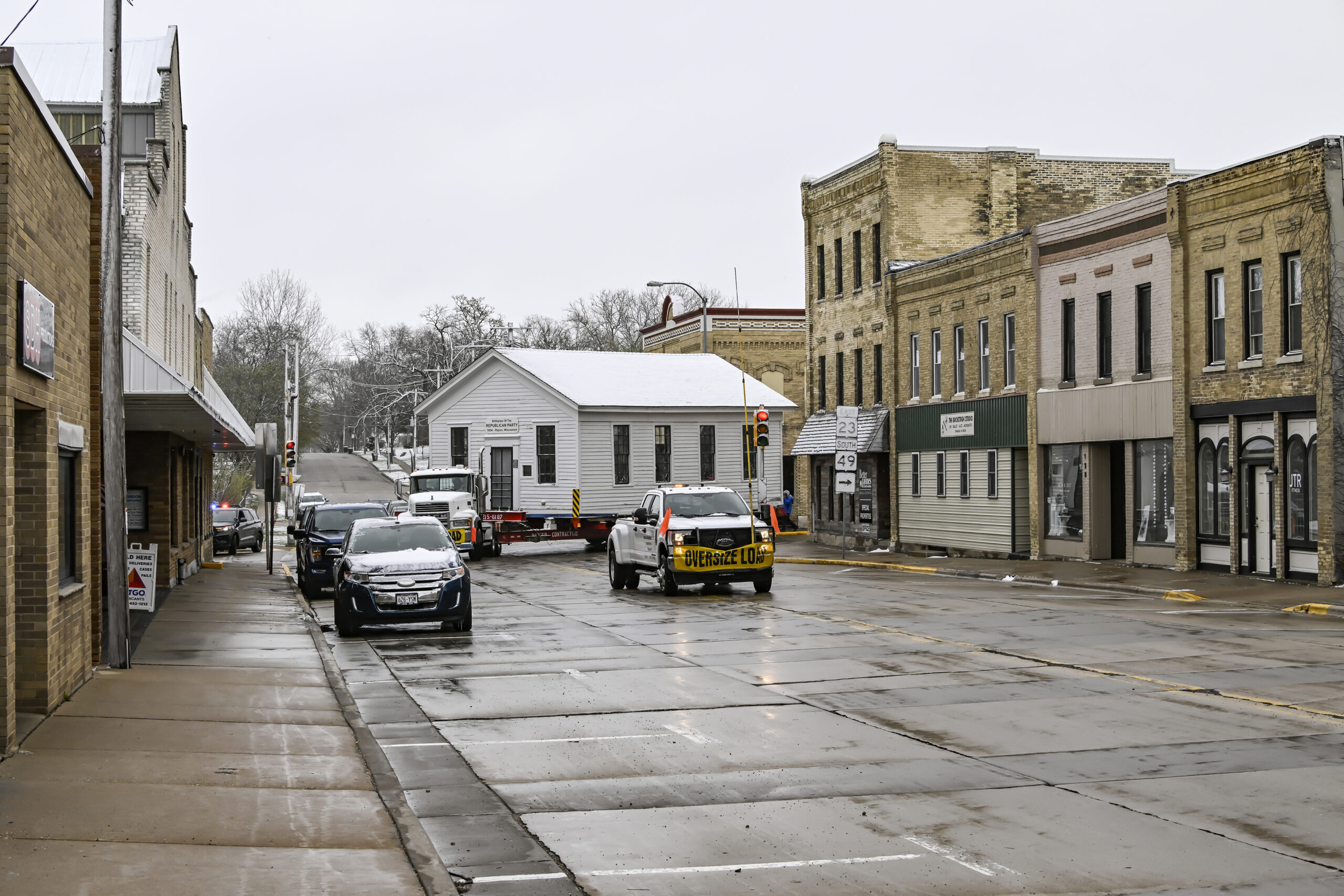 A truck carrying the Little White Schoolhouse turns onto West Fond du Lac Street in Ripon.