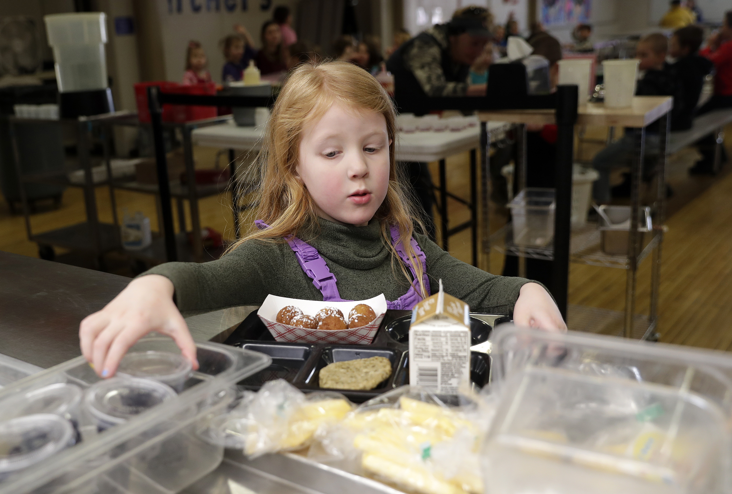 A kindergarten student at Suamico Elementary School chooses a cup of fruit while going through the hot lunch line