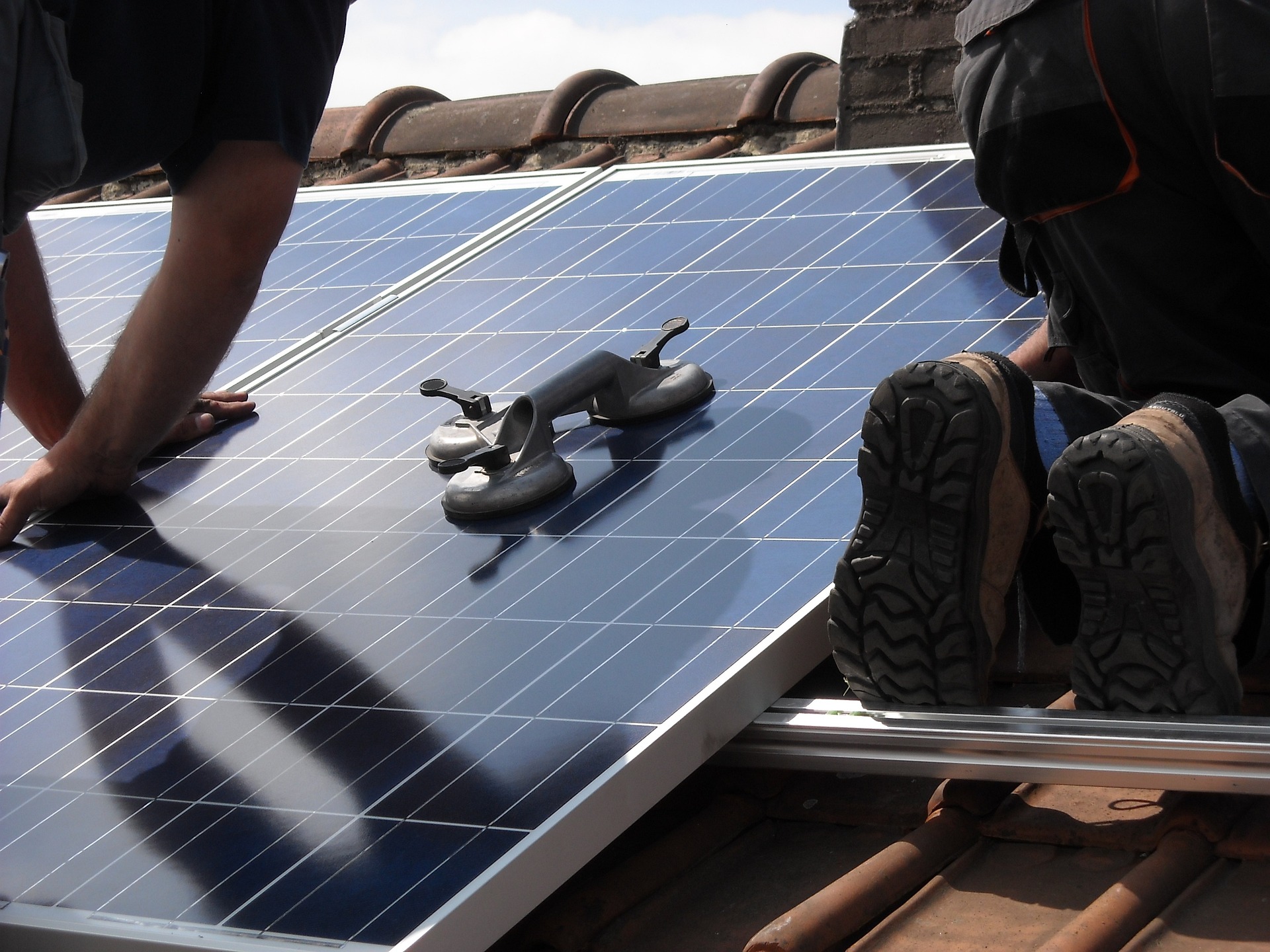 Worker placing solar panels on roof.