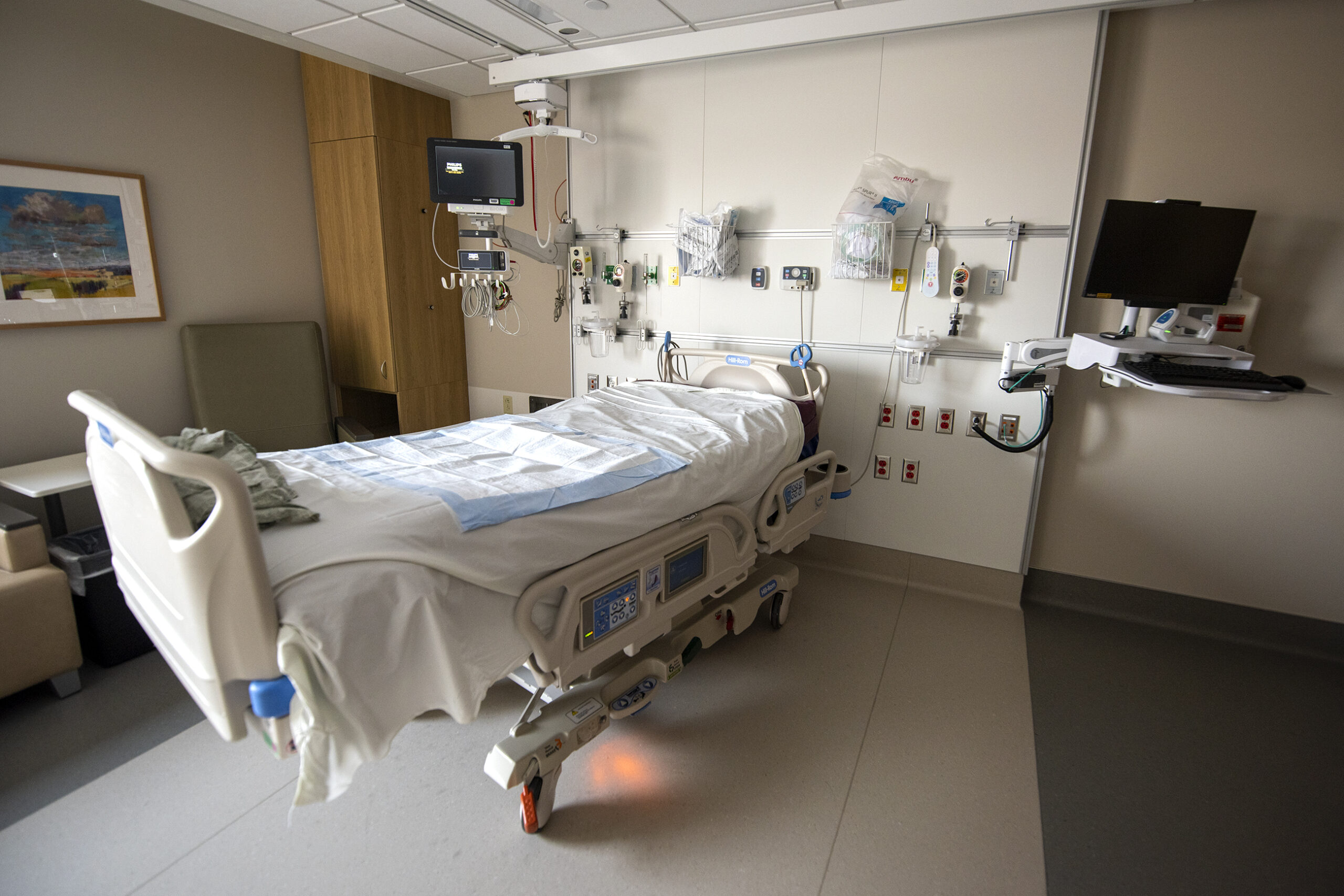 An empty hospital bed is surrounded by medical equipment.