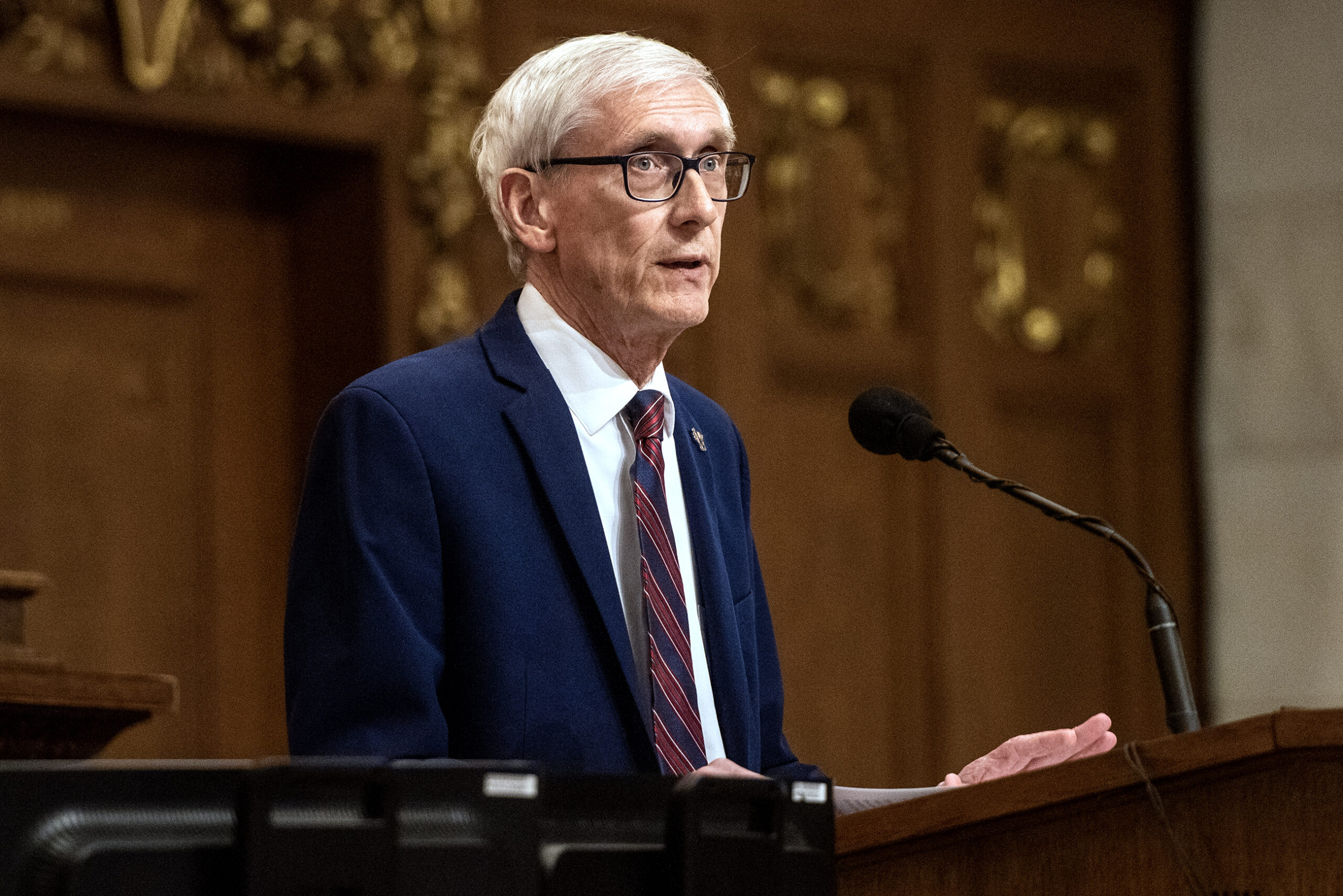 Gov. Tony Evers stands at a podium during a speech.