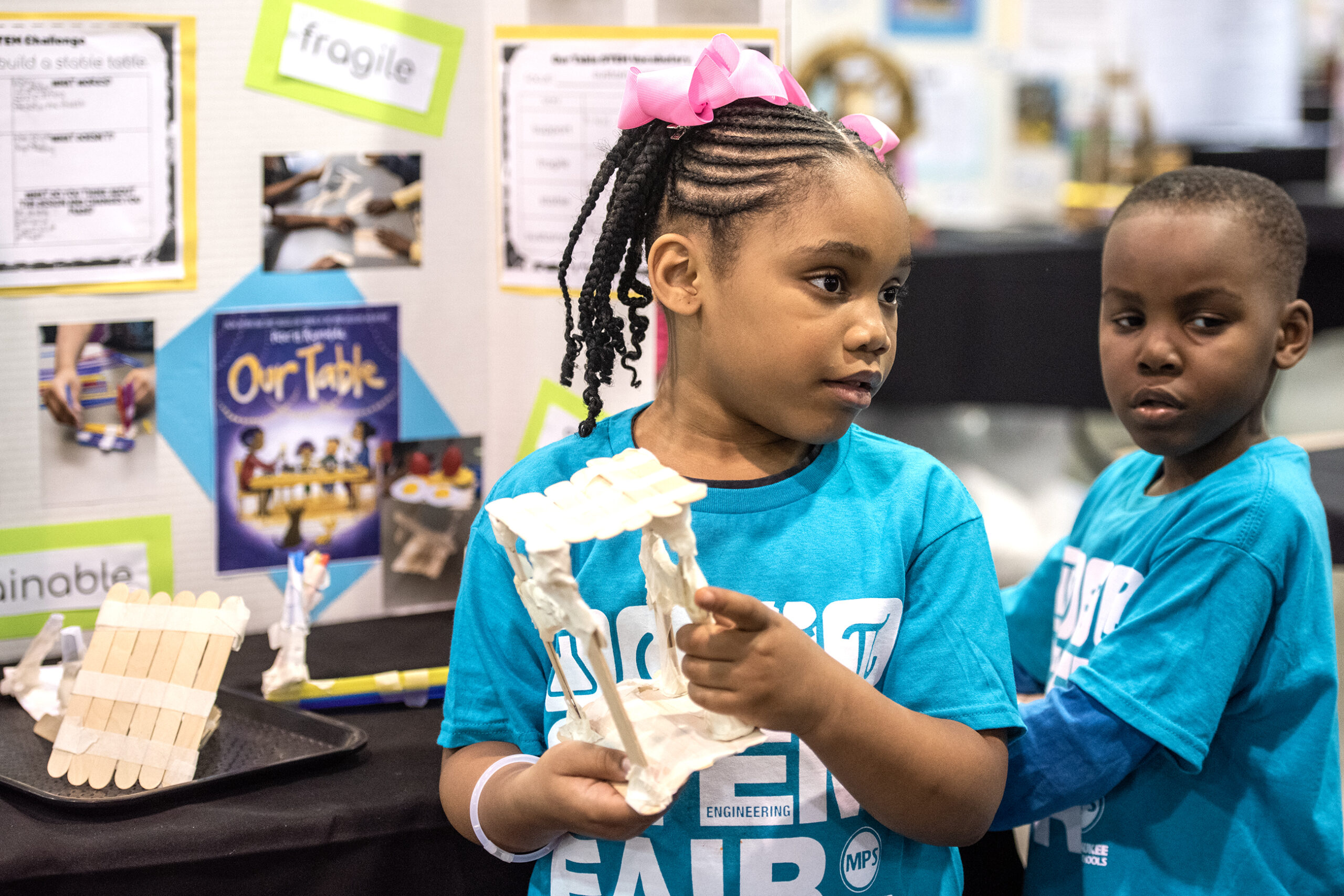 A young girl holds at table she created for the fair.