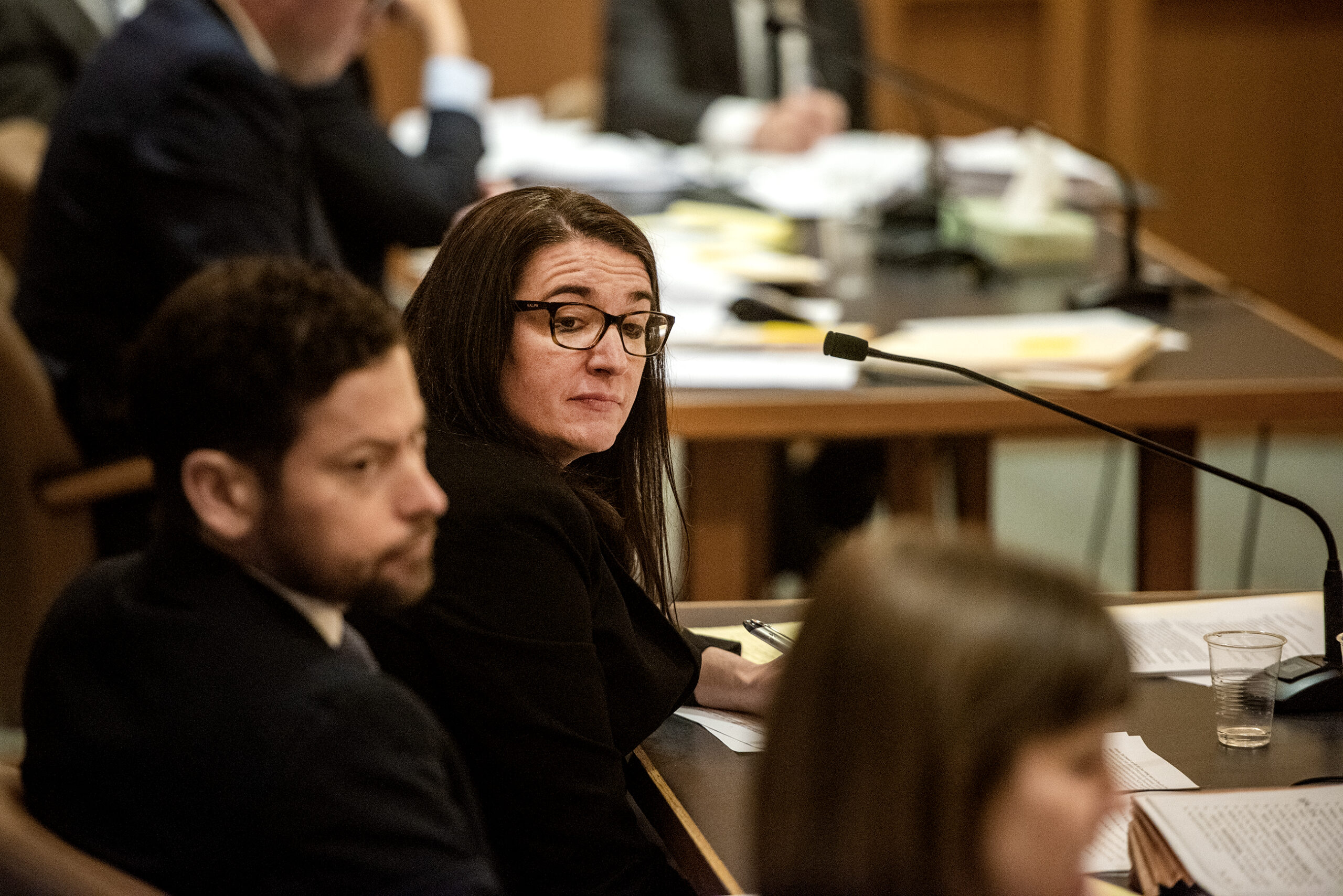 An attorney looks over as another attorney speaks.