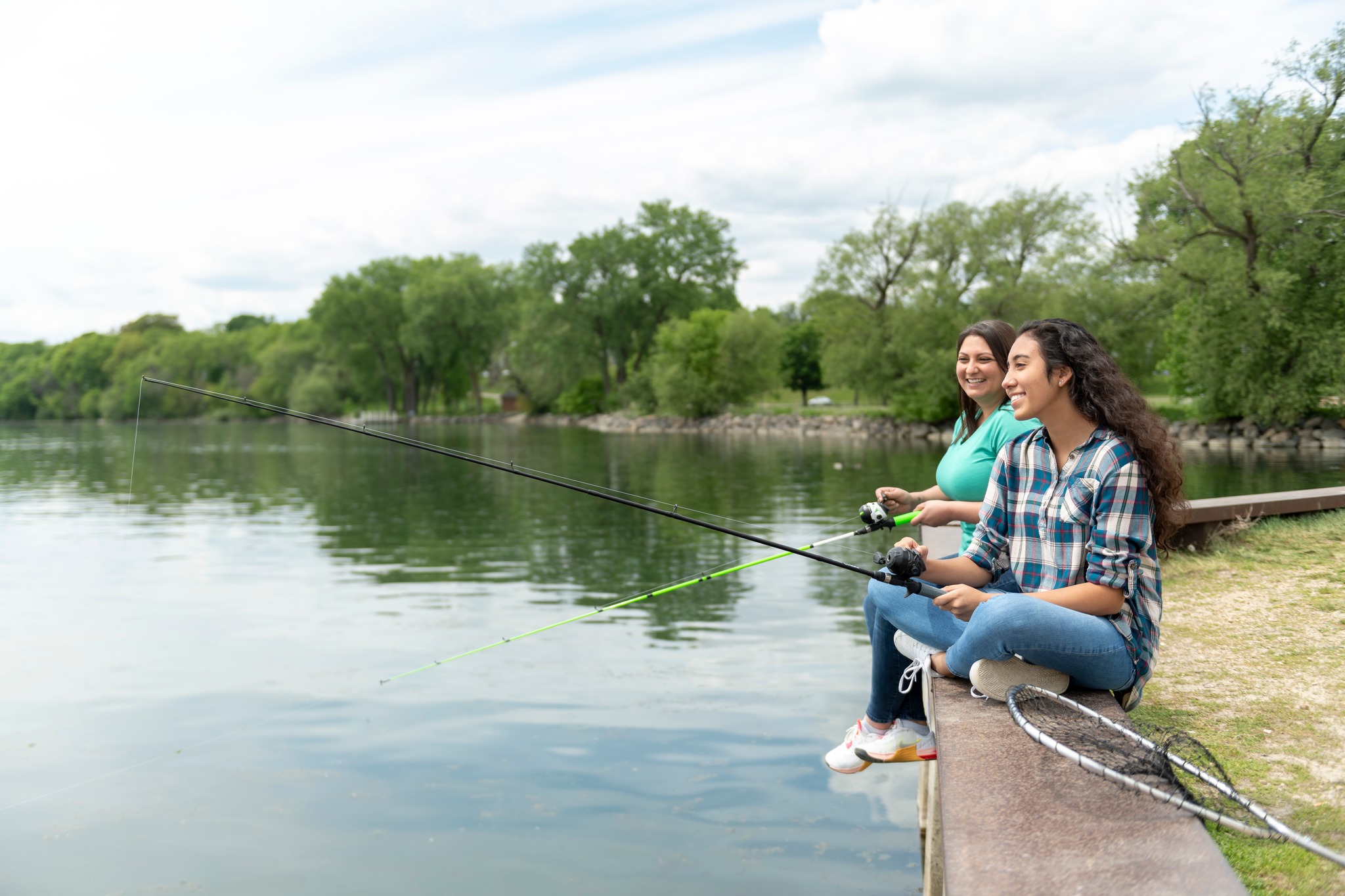 Two people fishing on the side of a lake