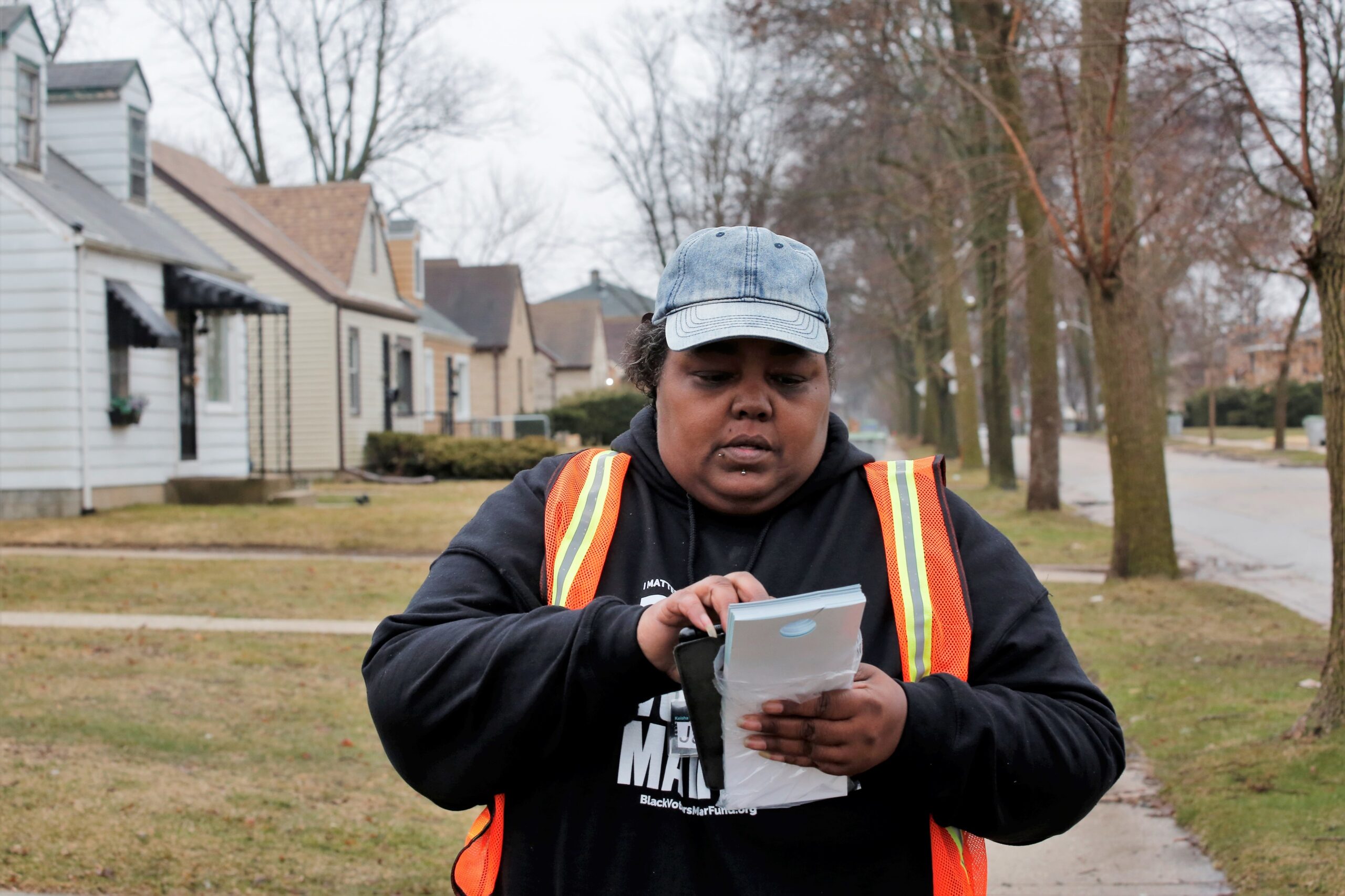 BLOC canvasser Janice Agnew checks addresses before knocking on doors and greeting residents in Milwaukee, reminding people to vote on April 4, 2023