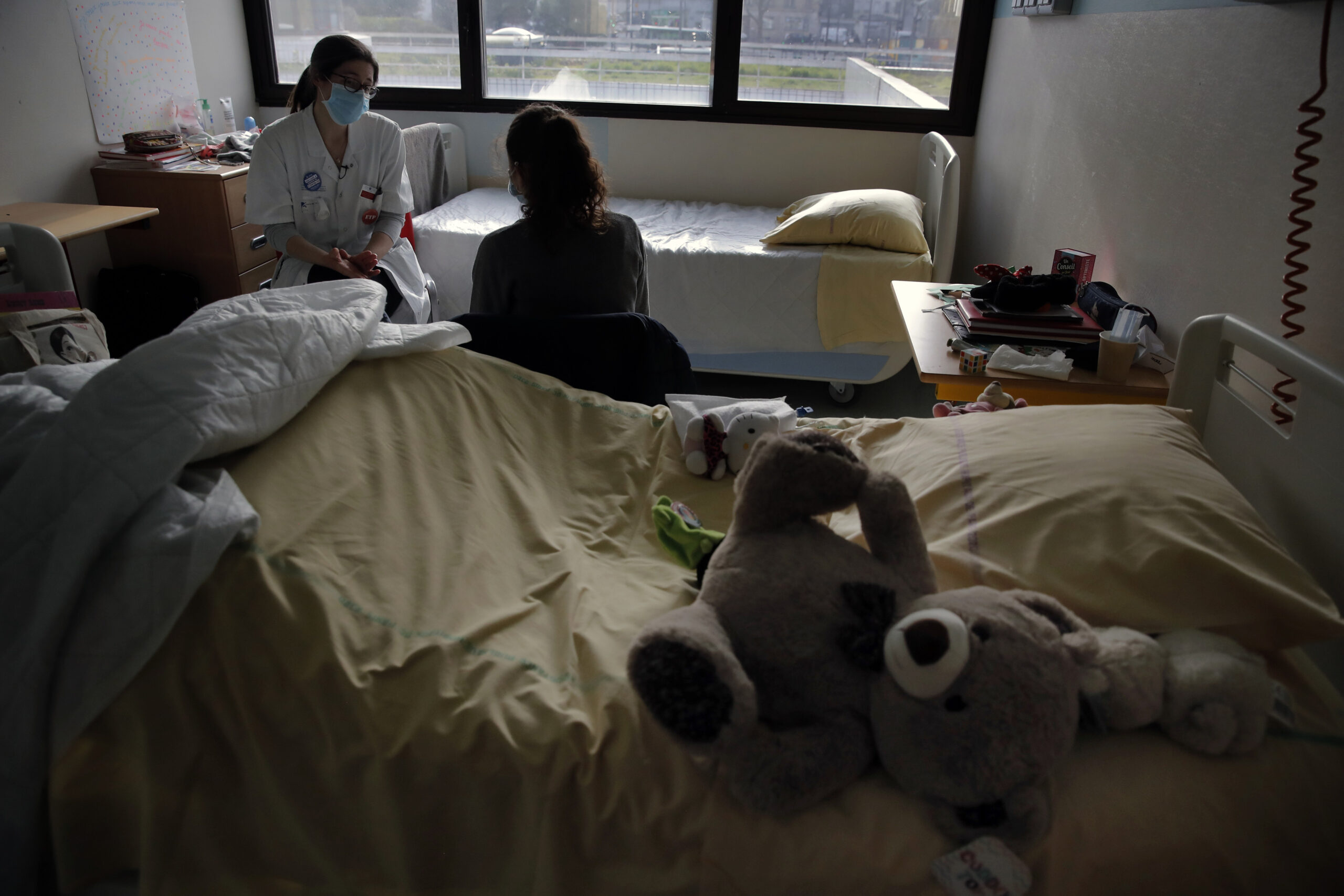 Psychiatrist Coline Stordeur speaks with a young girl in her hospital room.