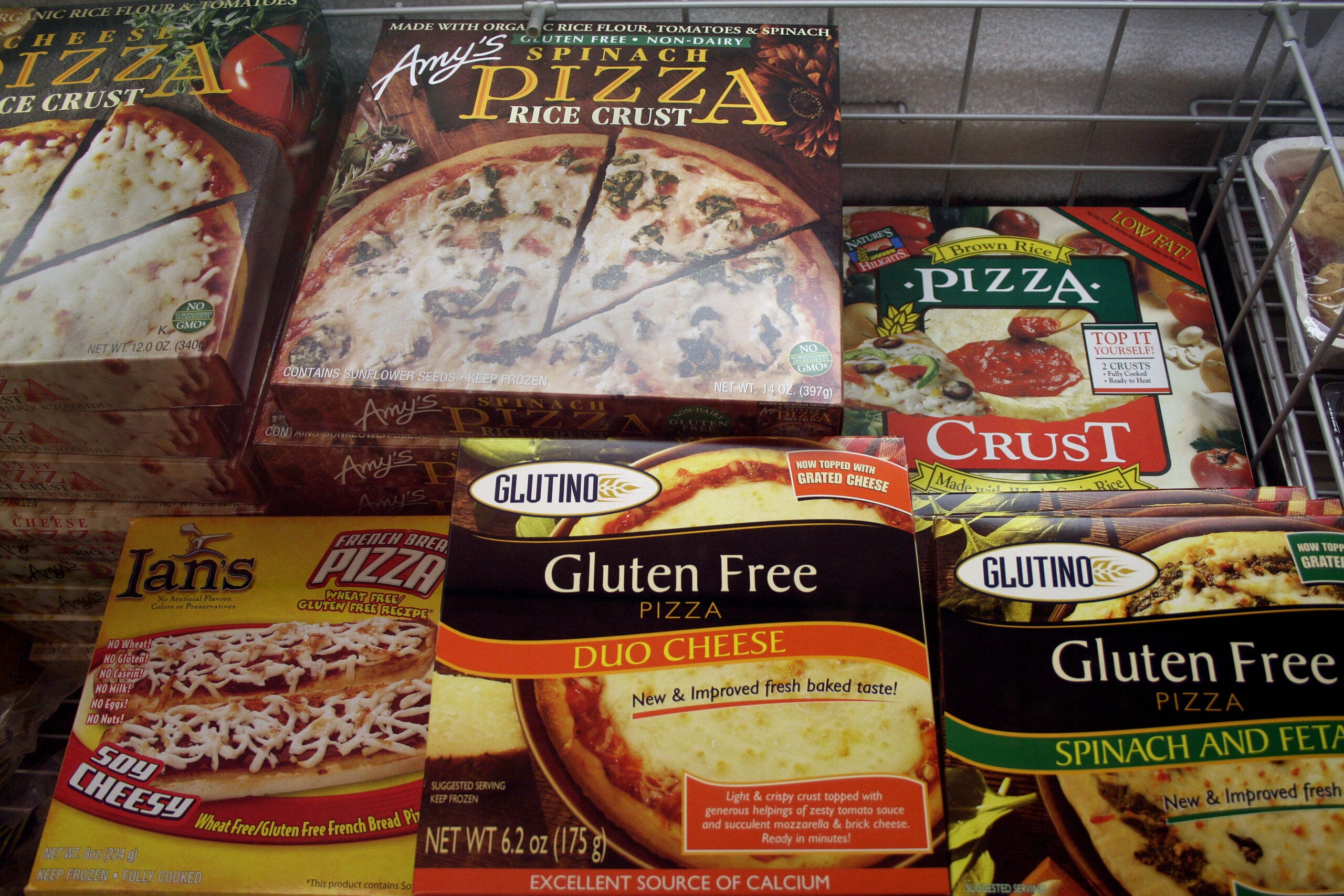 Gluten free pizzas are stacked in a chest freezer.