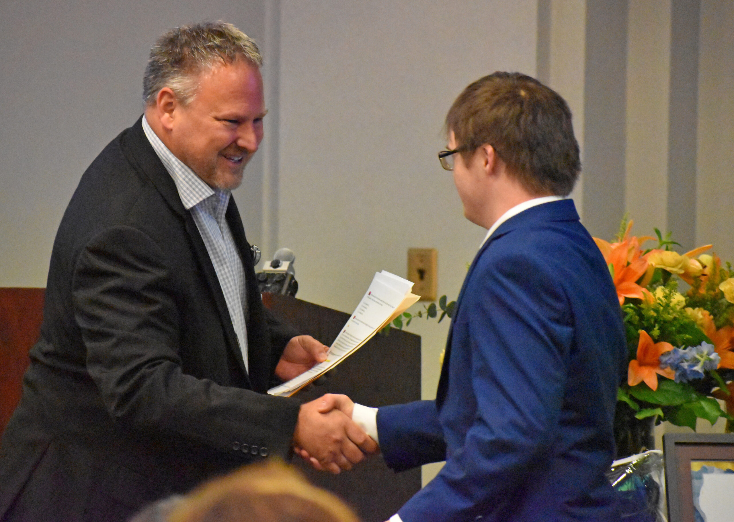 Intern Drew Gustin, right, shakes hands with Jeffrey Waise during the Project SEARCH graduation ceremony