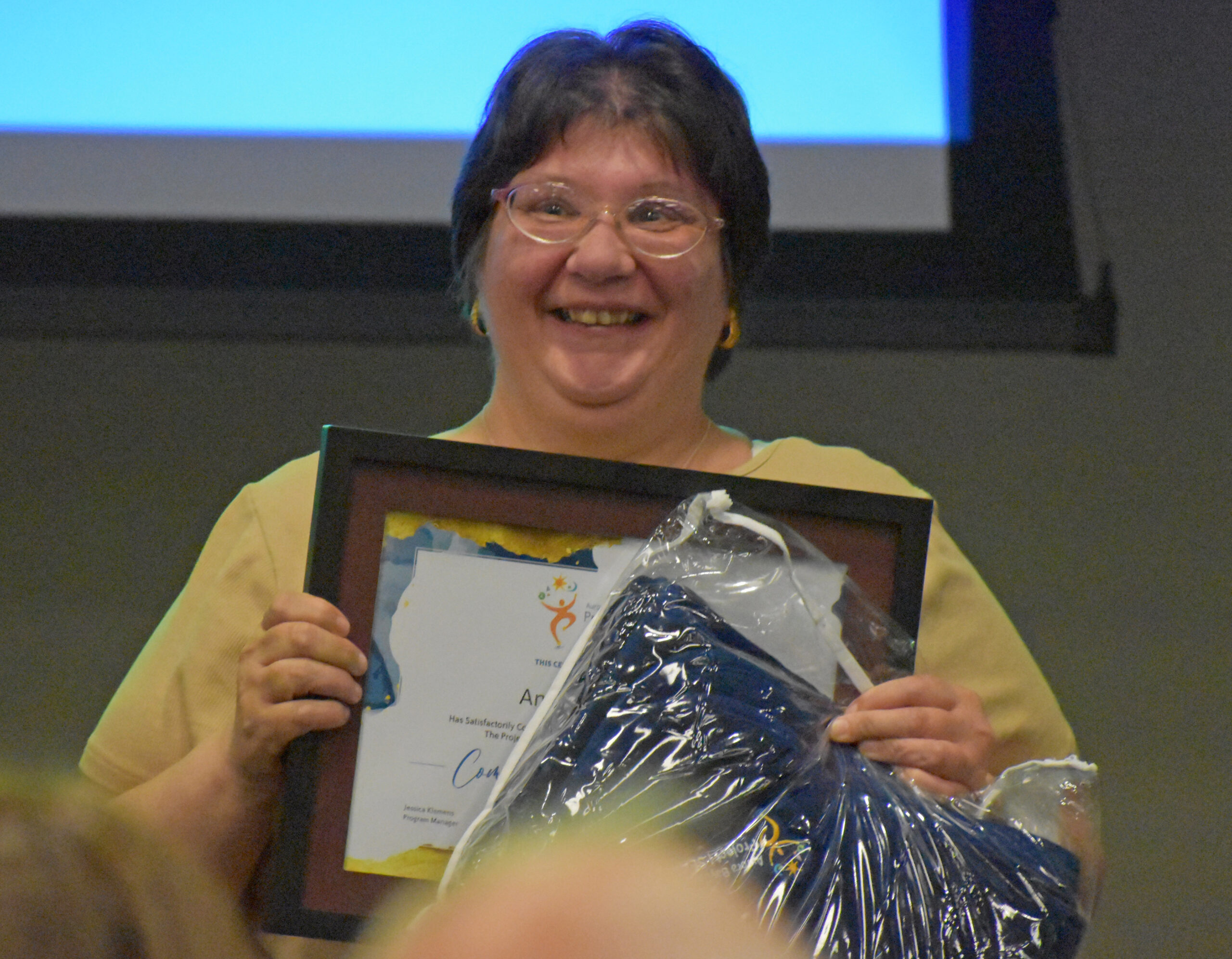 Angela Crowder smiles as she holds her Project SEARCH certificate at a graduation ceremony.