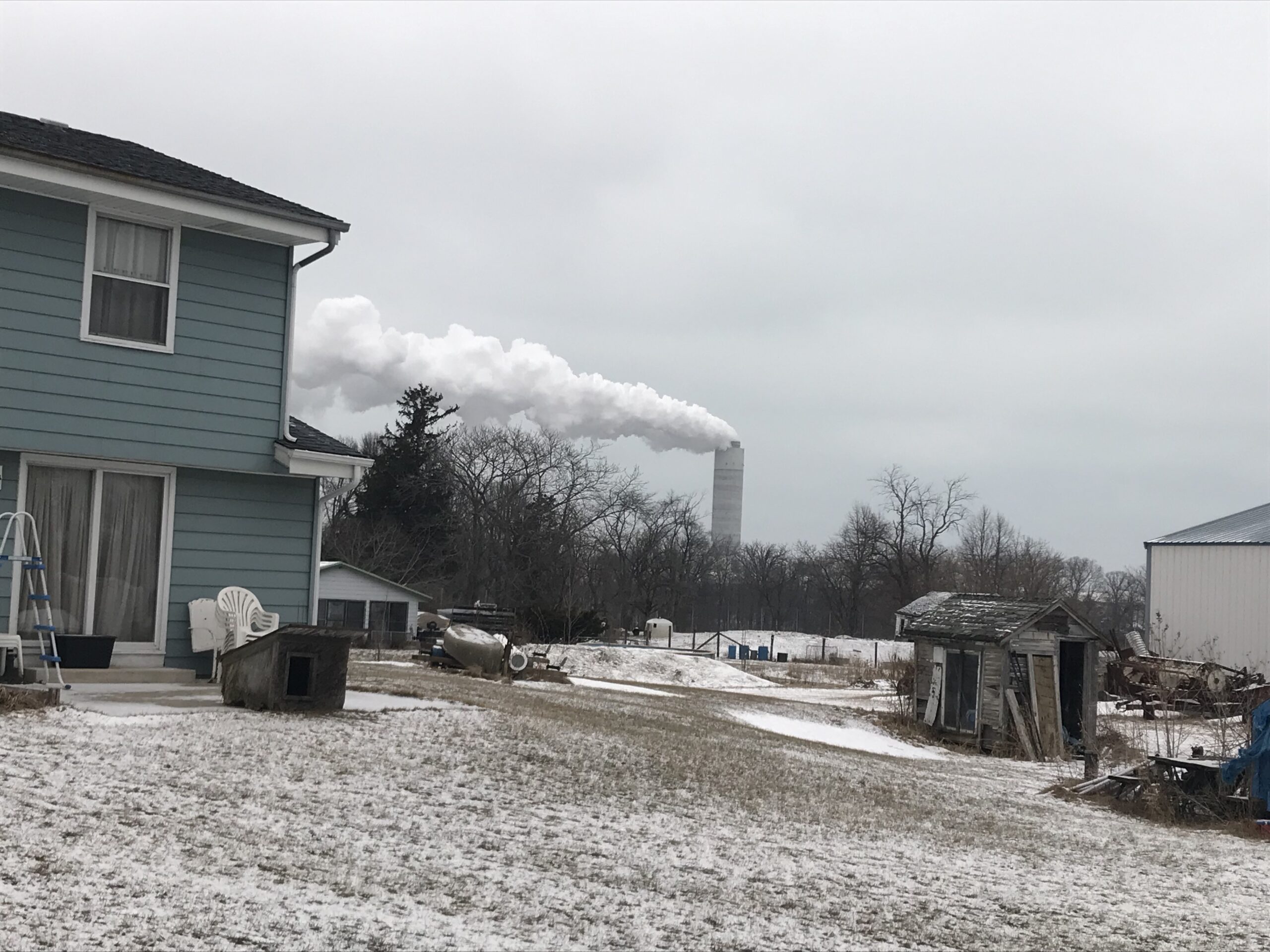 A power plant in the distance behind a house