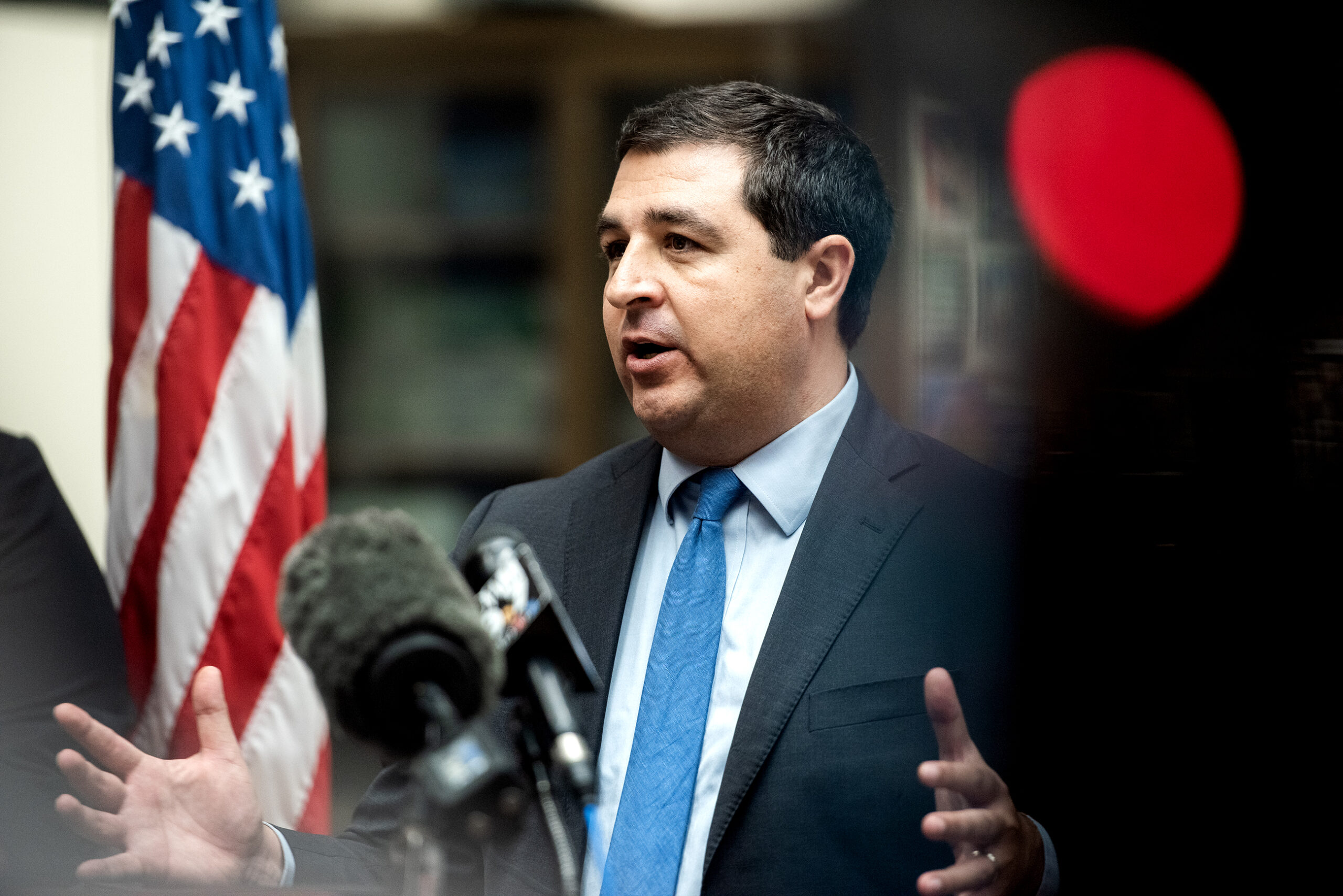 AG Josh Kaul is seen at a press conference with a red light from a camera in the corner.