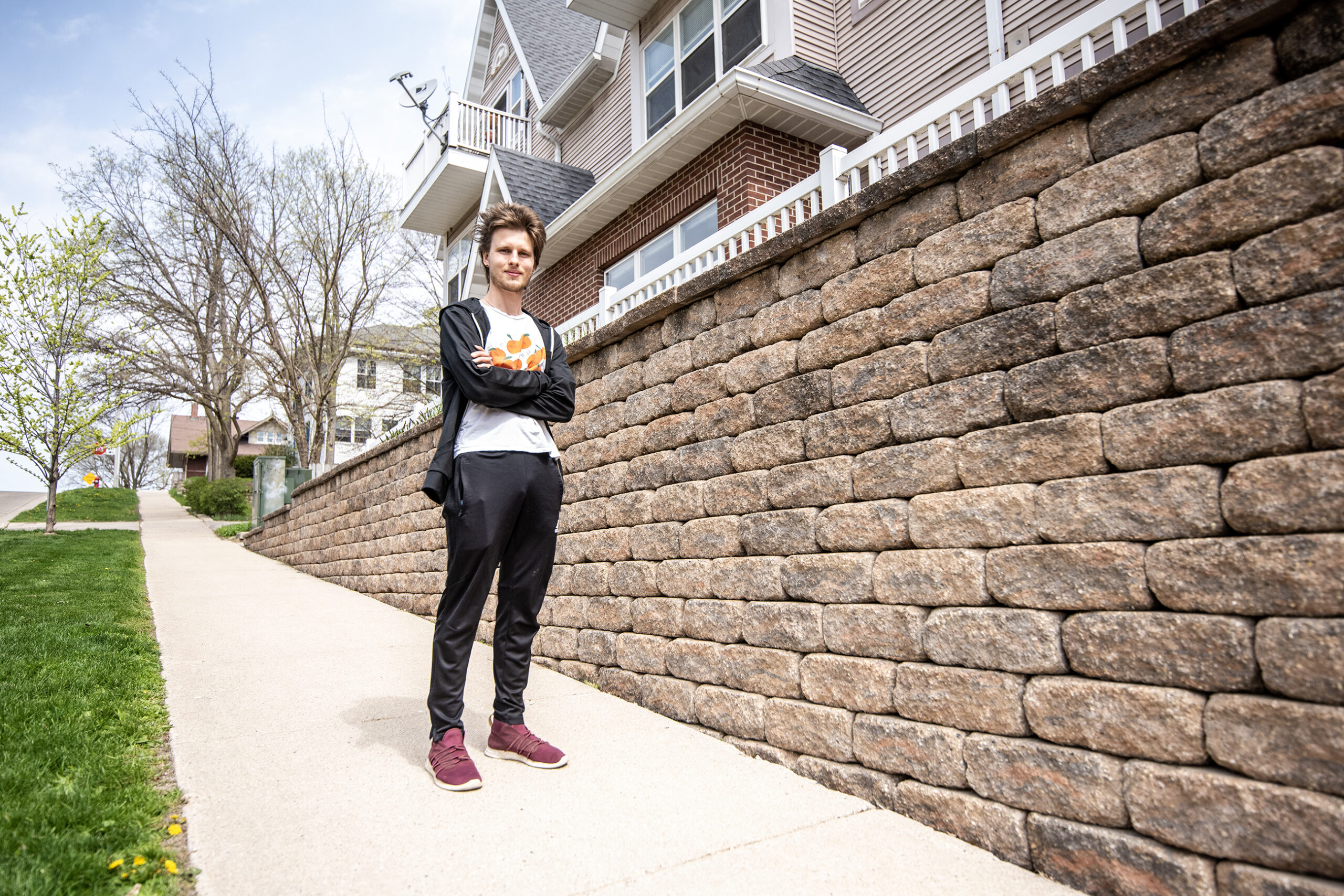 A man stands on a sidewalk near homes.