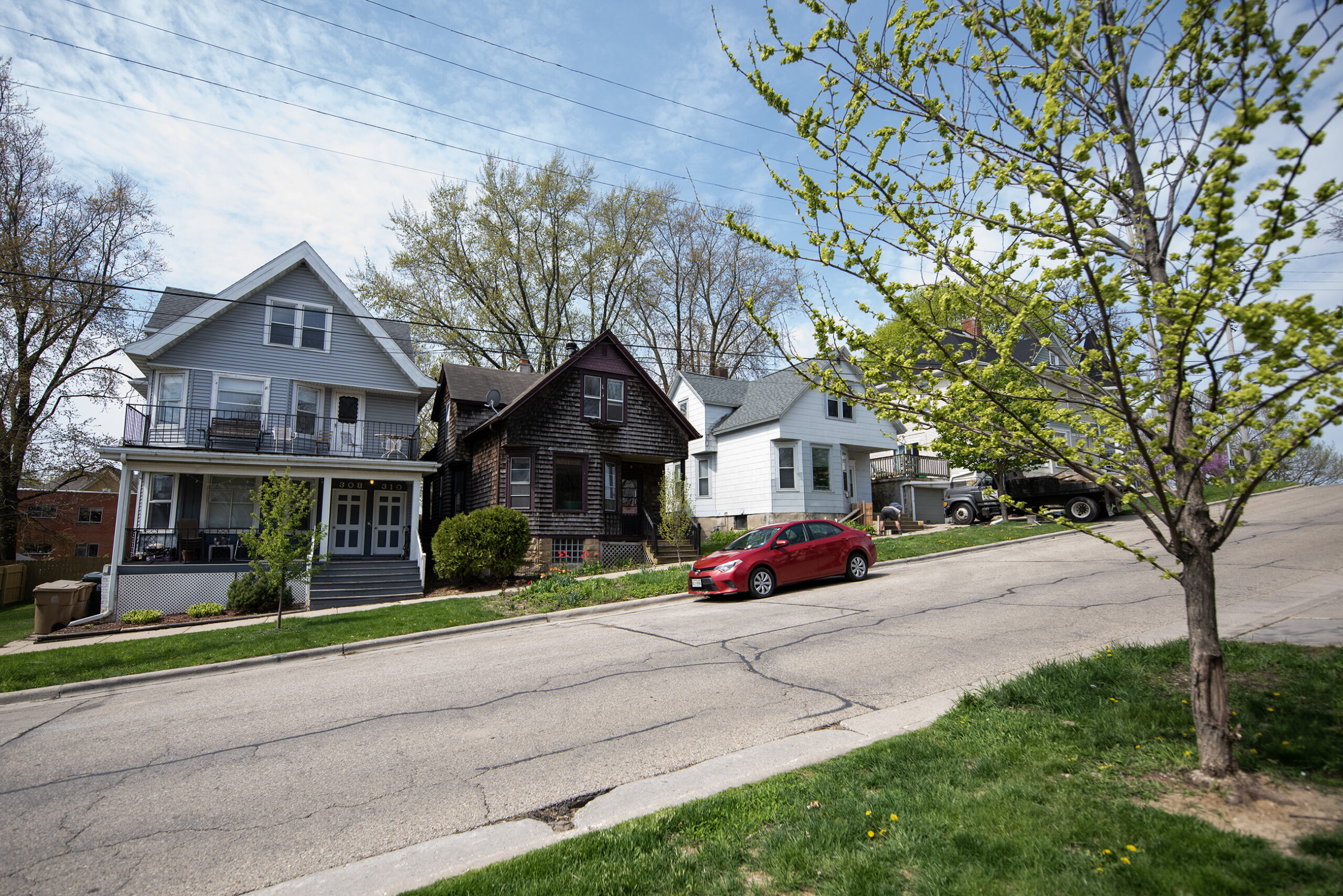 Three homes are seen along a sloped street.