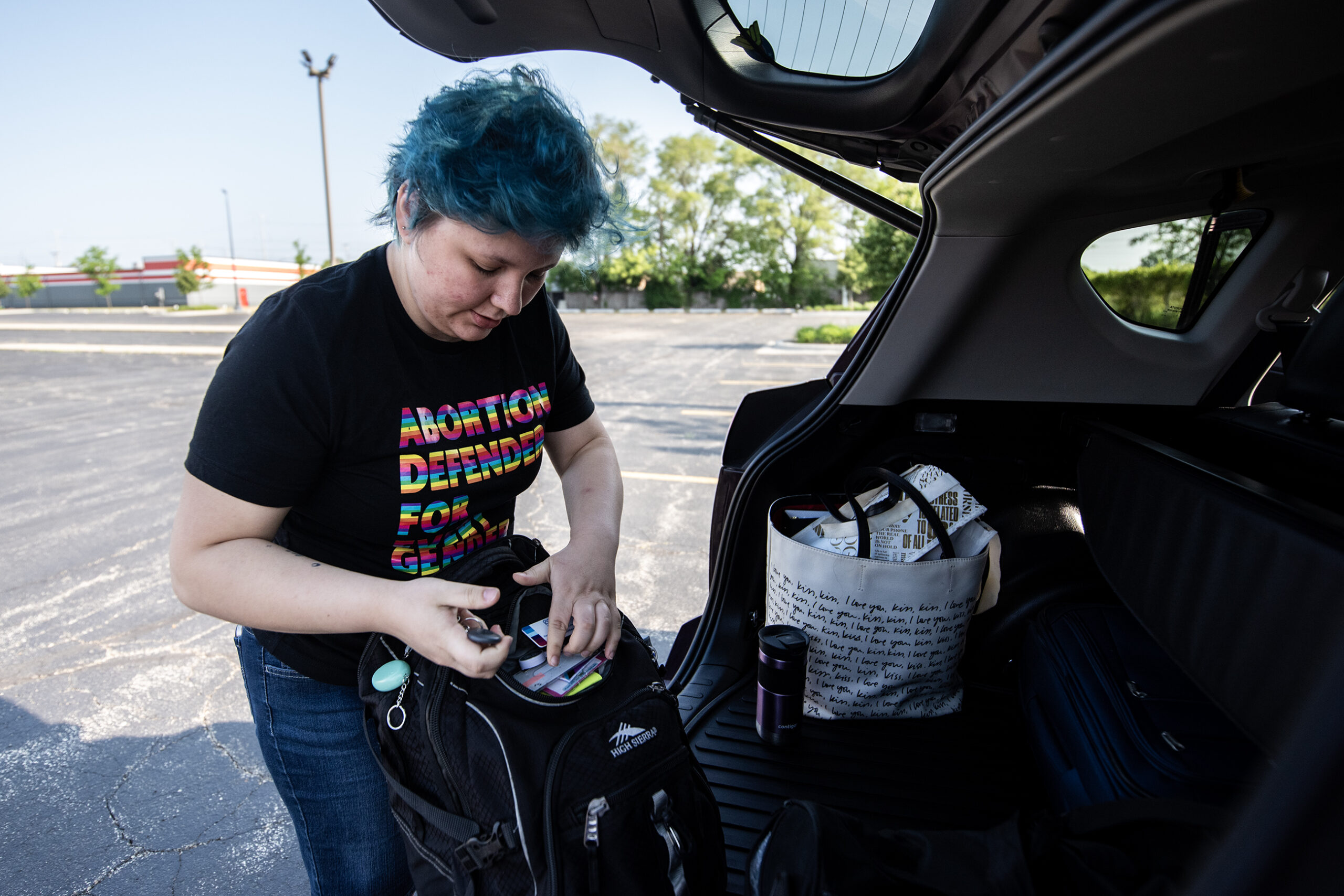 A person grabs a backpack out of a trunk.