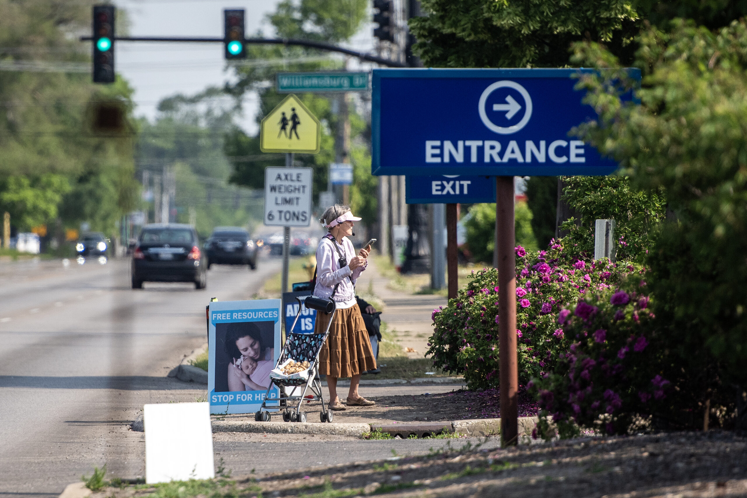 A woman with a headset on stands near pro-life signs.