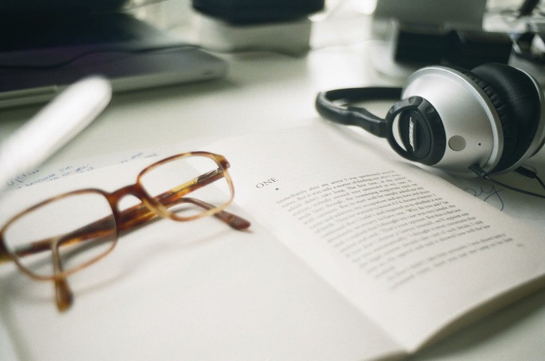 A pair of glasses sits on top of an open book.