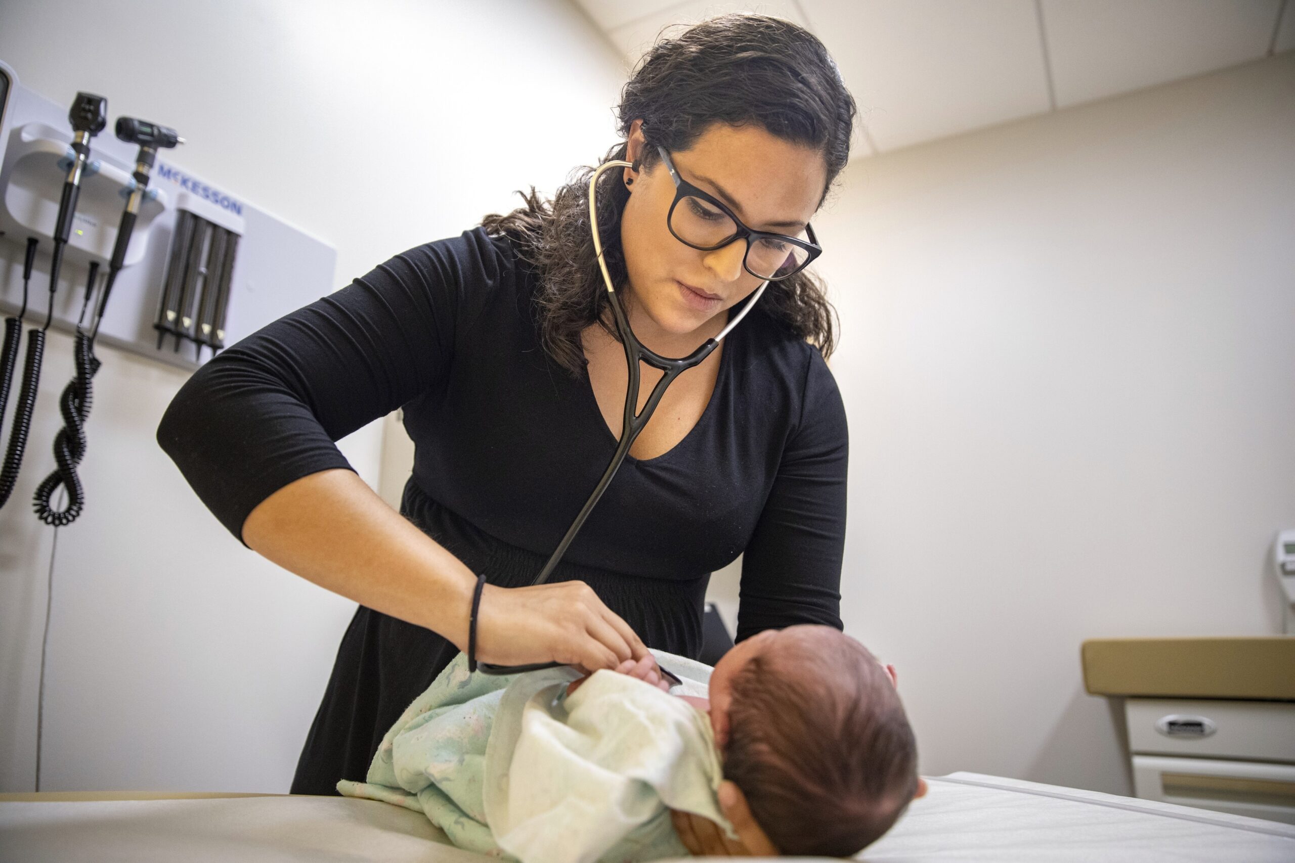 A pediatrician examines a newborn baby in her clinic.