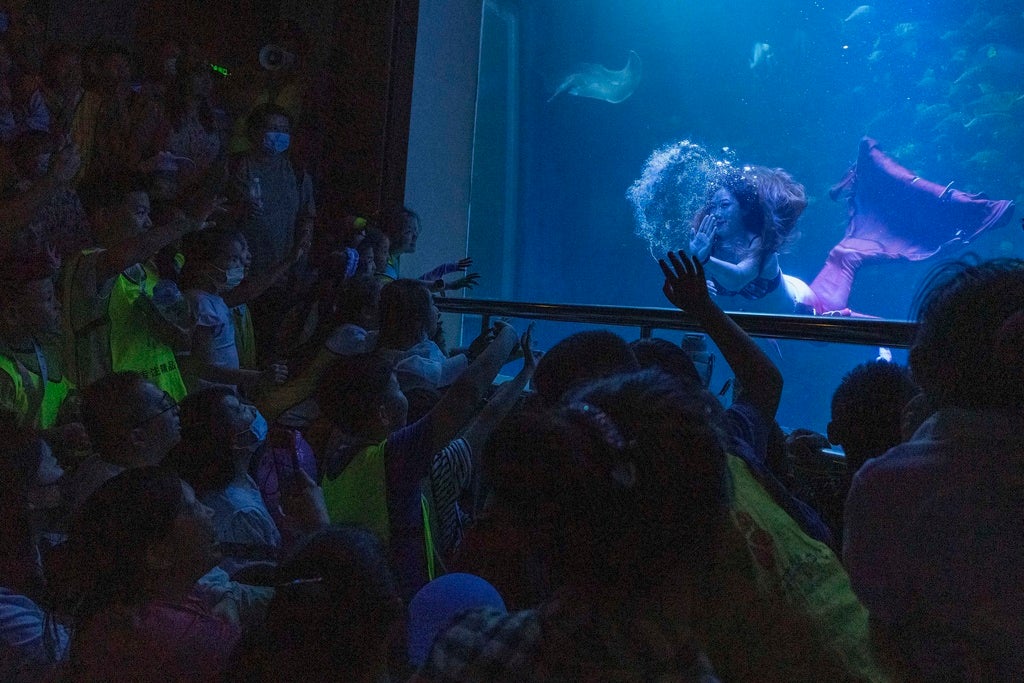 Visitors watch a performer dressed as a mermaid perform an underwater park on Children's Day in Beijing, Thursday, June 1, 2023. Children's Day is celebrated on June 1 in Communist and post-communist countries. (AP Photo/Ng Han Guan)