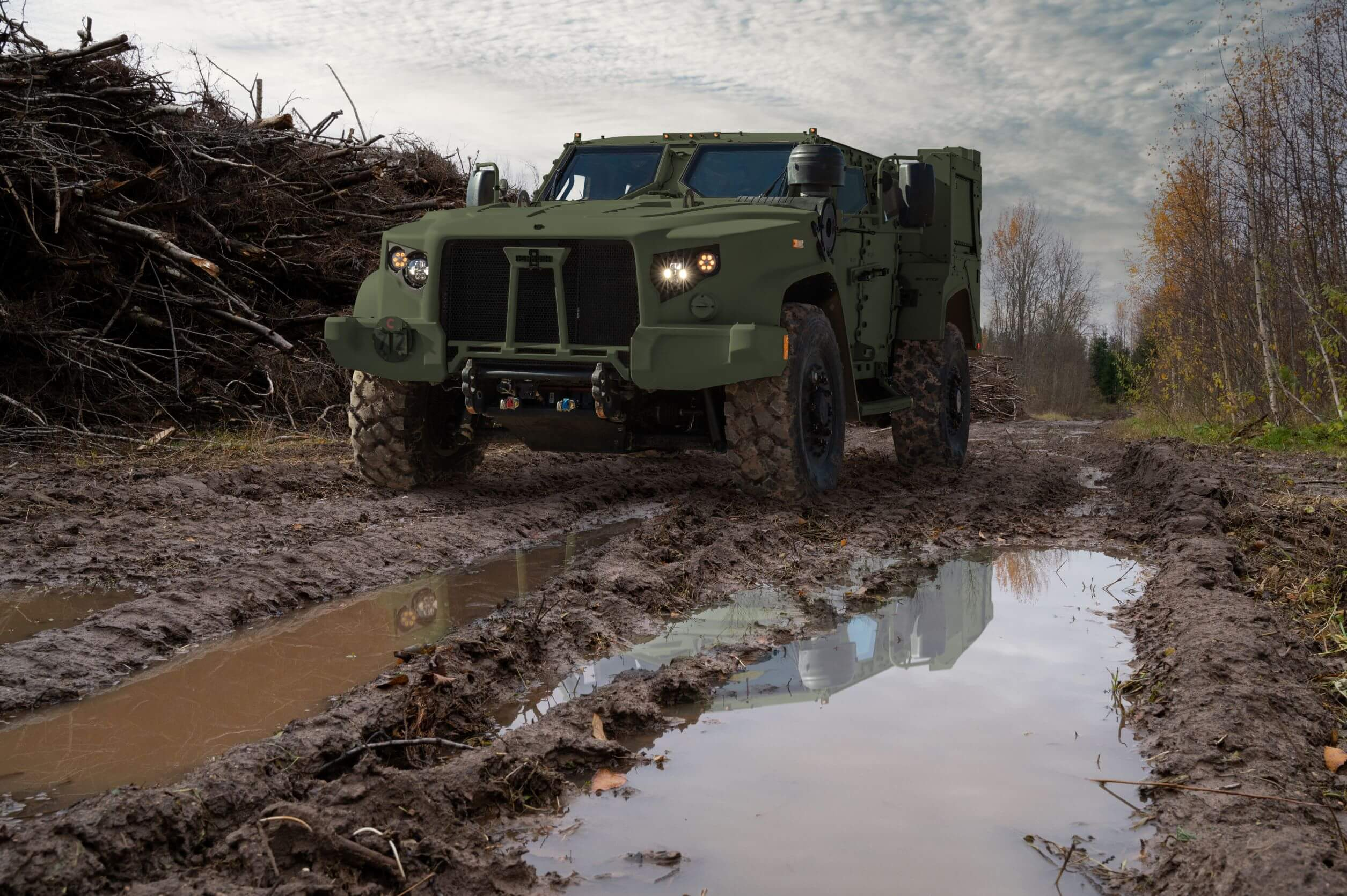 An Oshkosh Defense Joint Light Tactical Vehicle drives through muddy terrain.