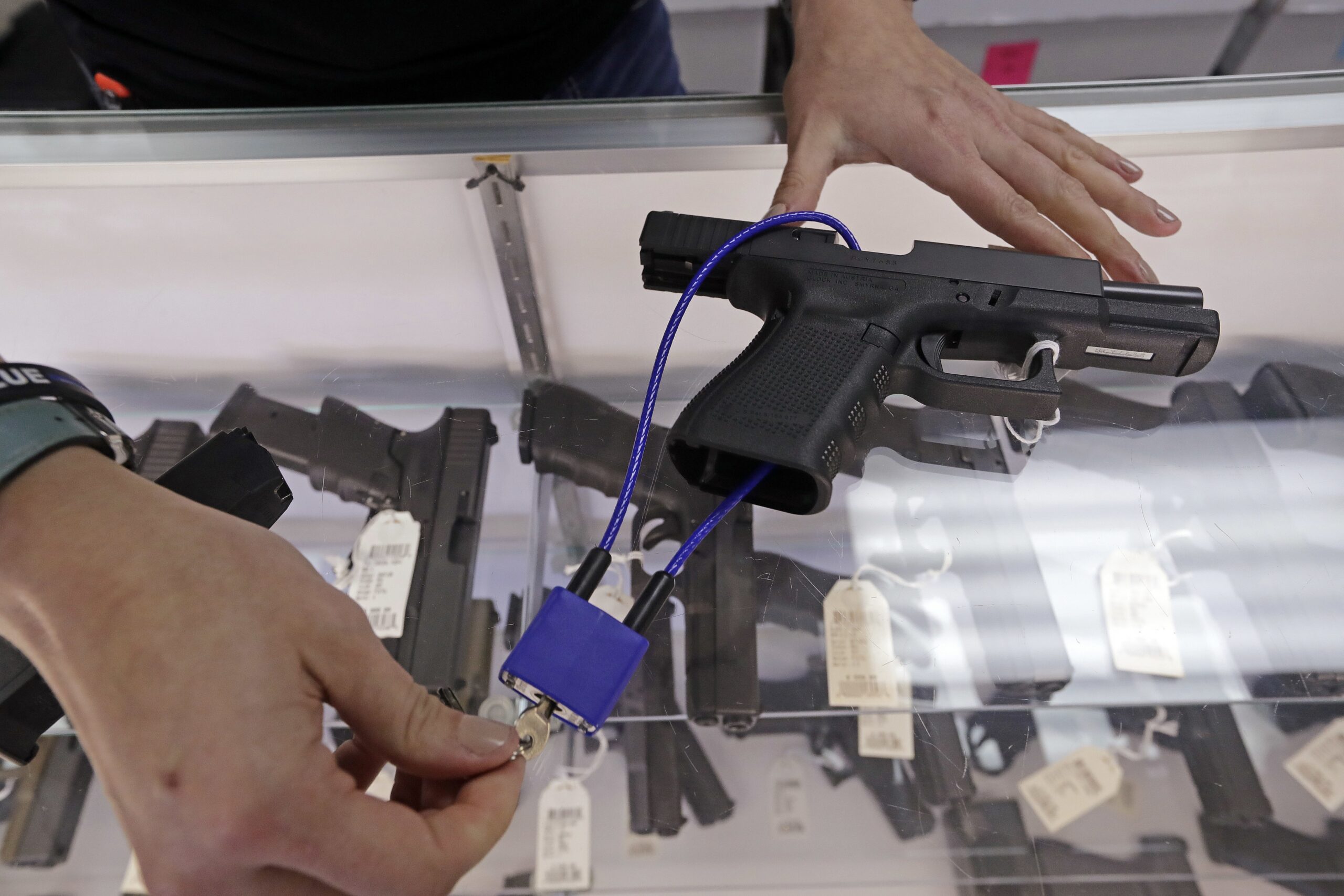 A gun shop owner demonstrates how a gun lock works.