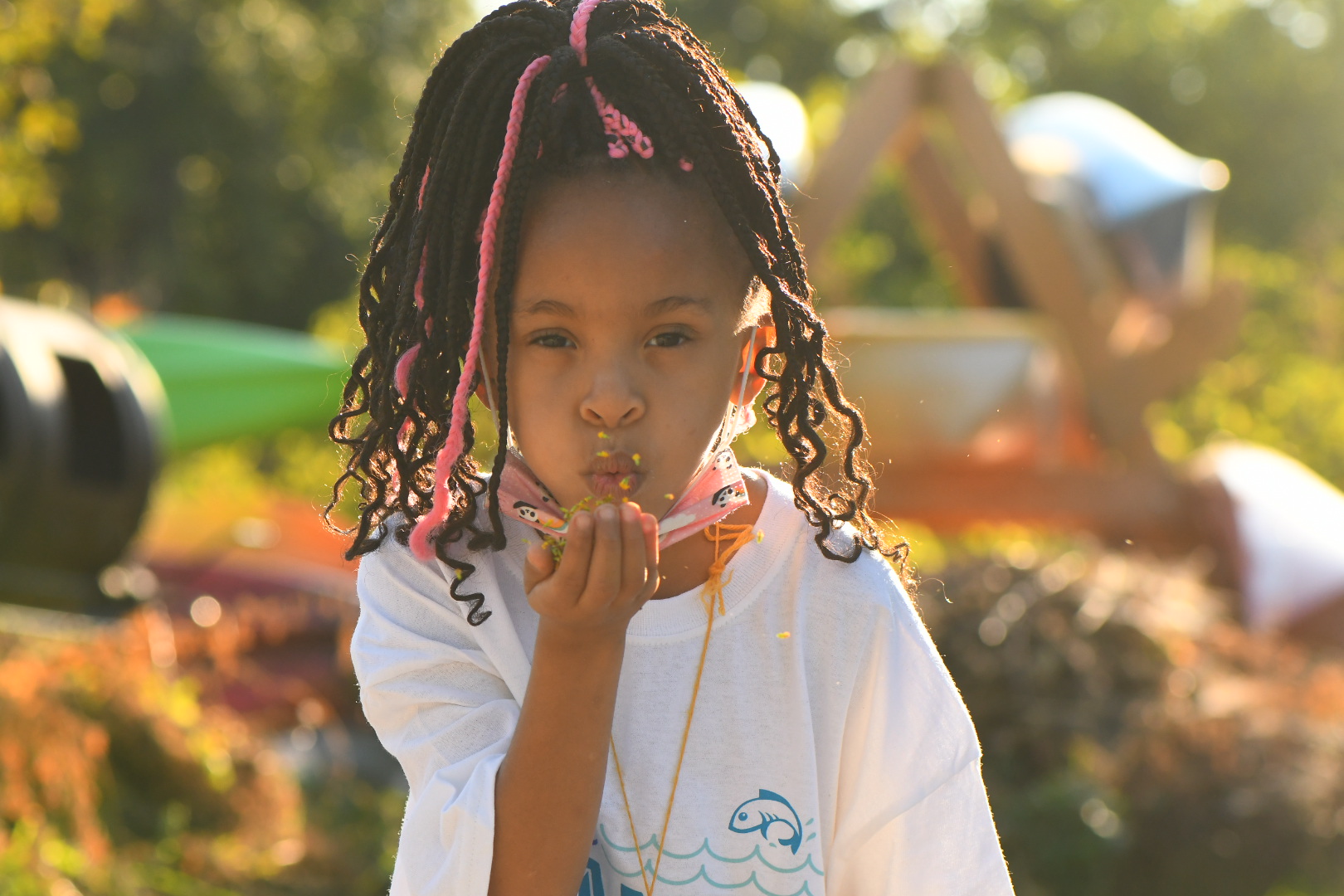 A young girl blows flower petals at the camera