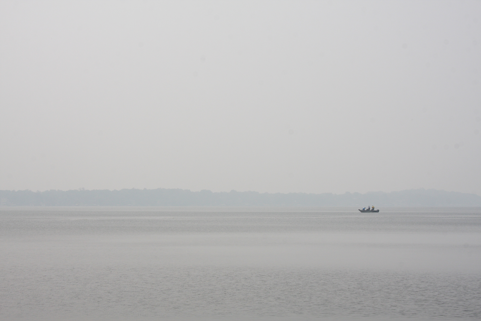 A boat on the water surrounded by a smoky haze caused by wildfires in Canada