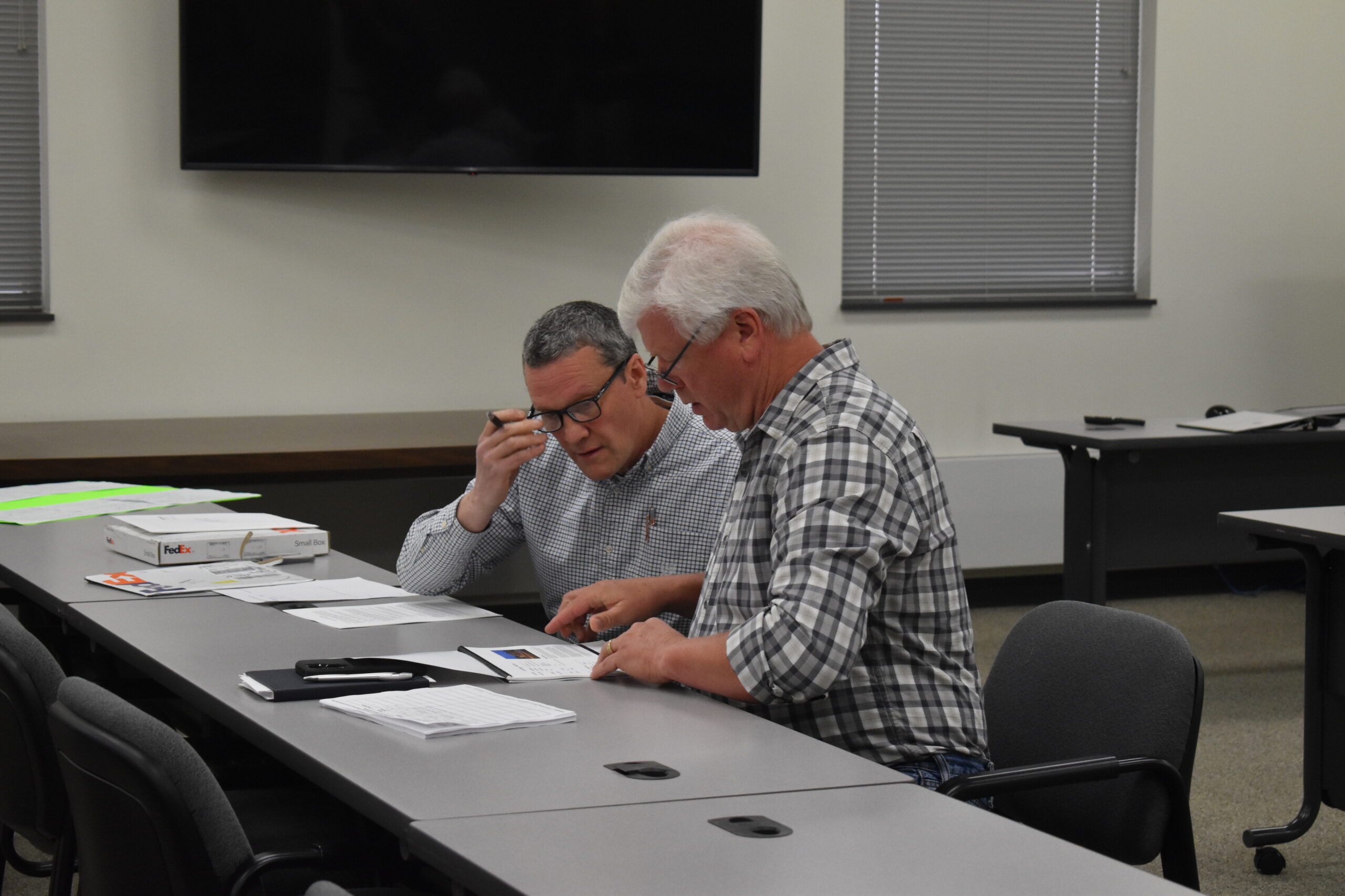 Lincoln County Clerk Christopher Marlowe, left, and County Board chair Don Friske review three offers from brokers
