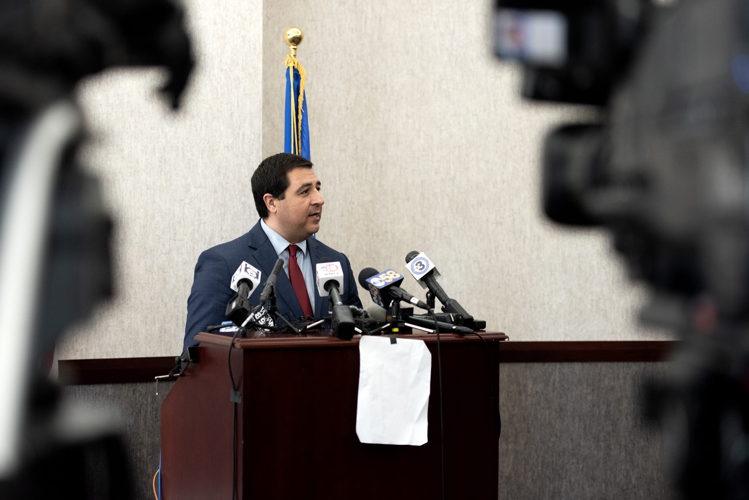 AG Josh Kaul stands in front of microphones and cameras.