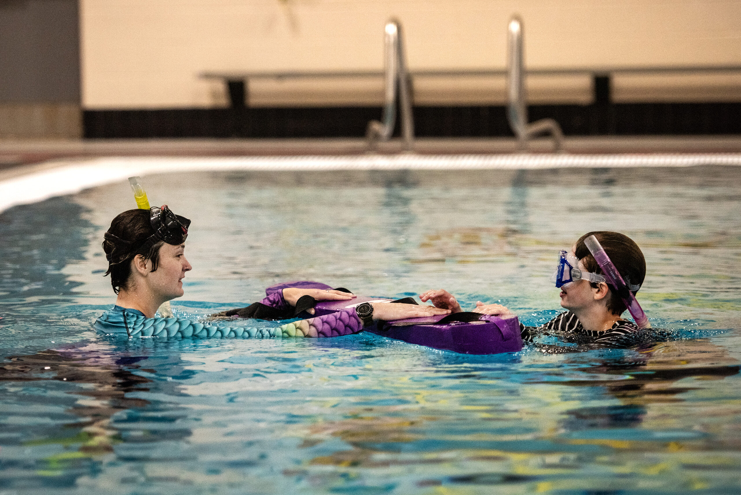 Two people swim in a pool.