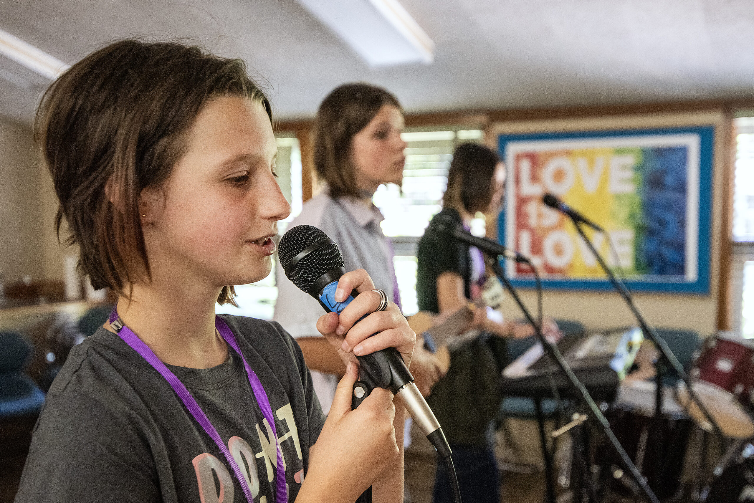 A camper stands at a microphone to sing with other musicians.