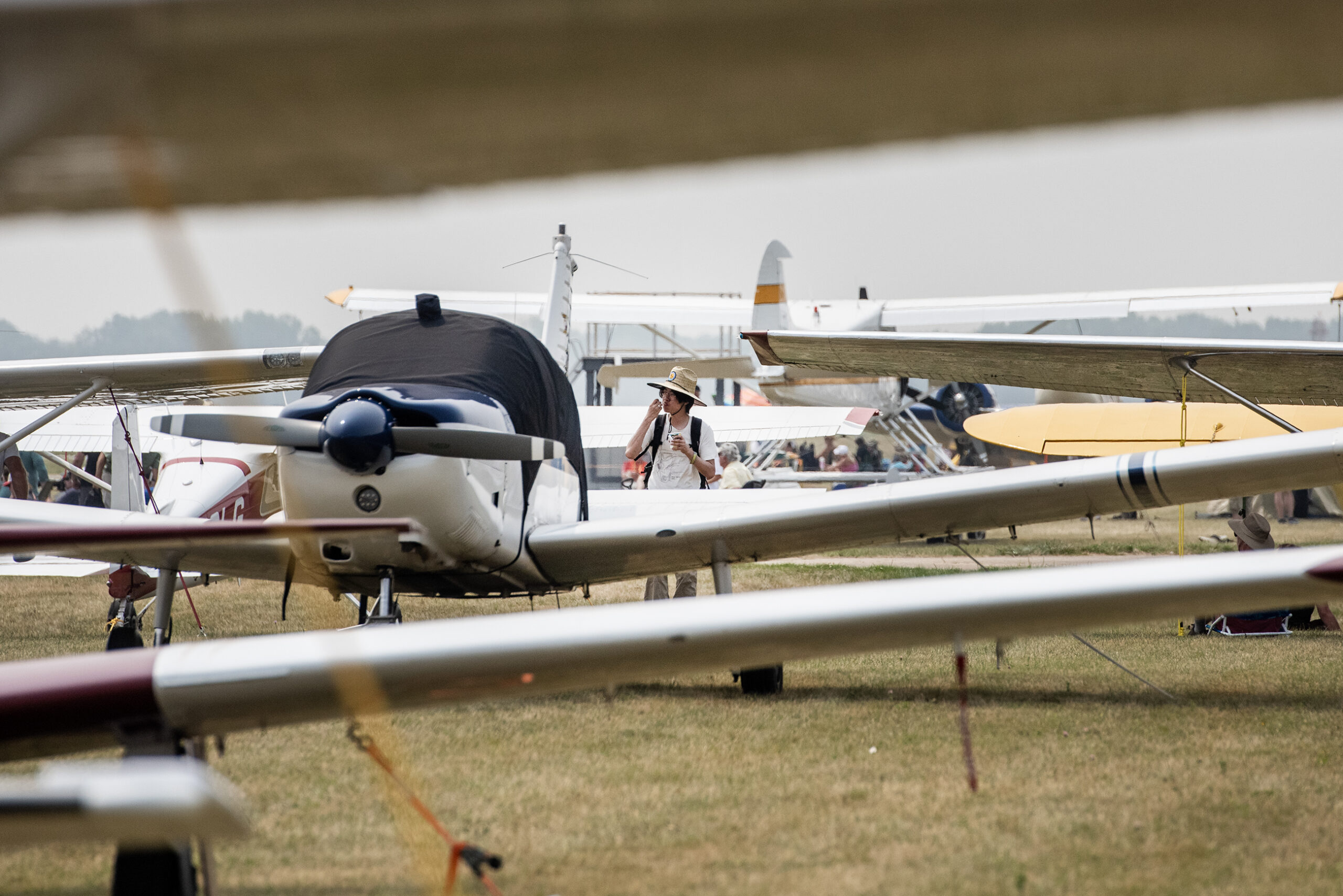 A man walks through a field where many airplanes are parked.