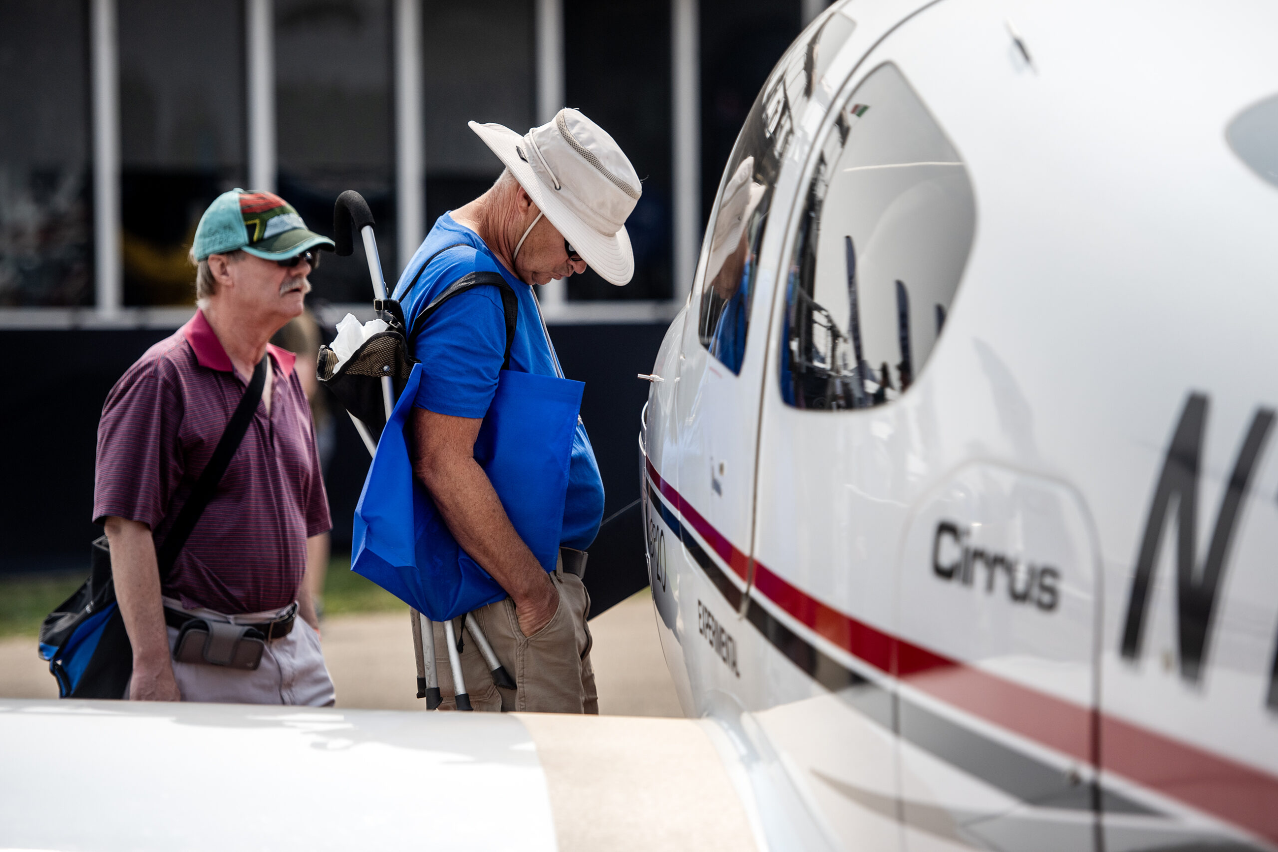 Two men look up close at a small white airplane.