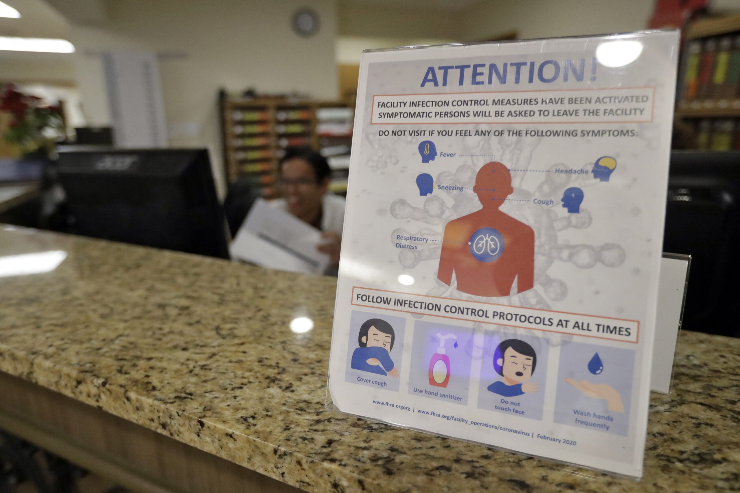 An infection control protocol poster sits on a nursing station desk