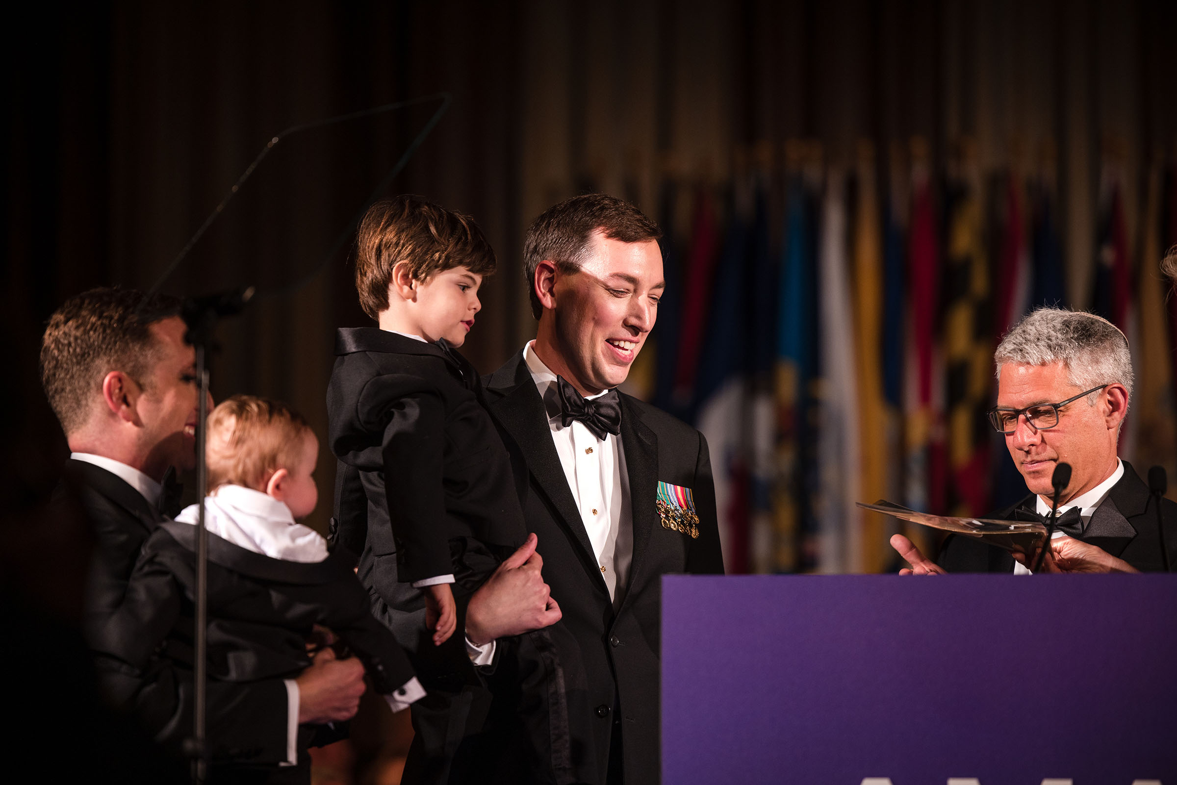 A man holds his child on stage during a ceremony where he gave an inaugural address as the American Medical Association's new president.