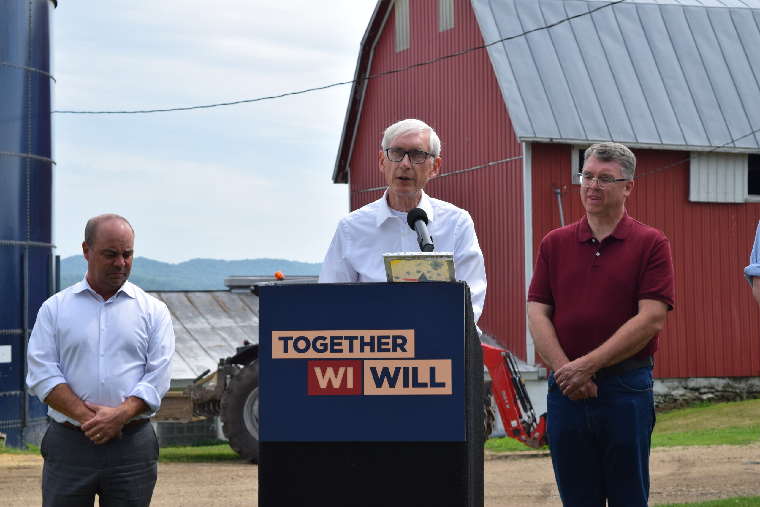 Evers talks about the state budget in front of a red barn