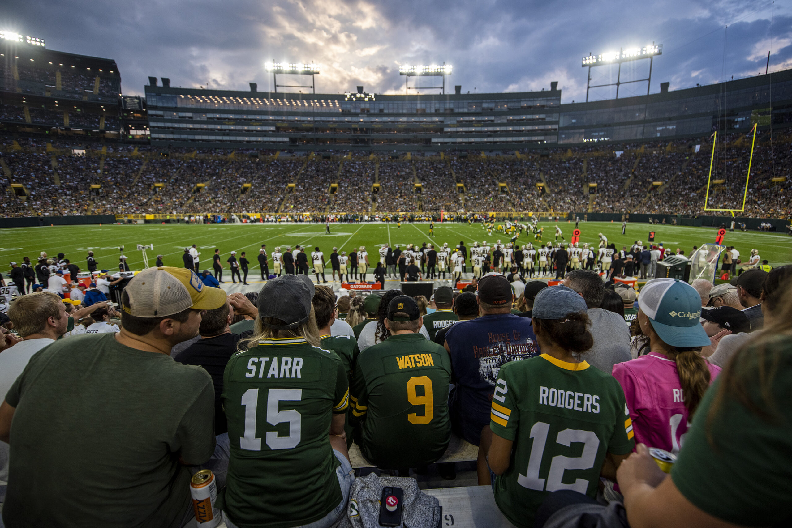Packers fans wear player jerseys as they sit in Lambeau Field.