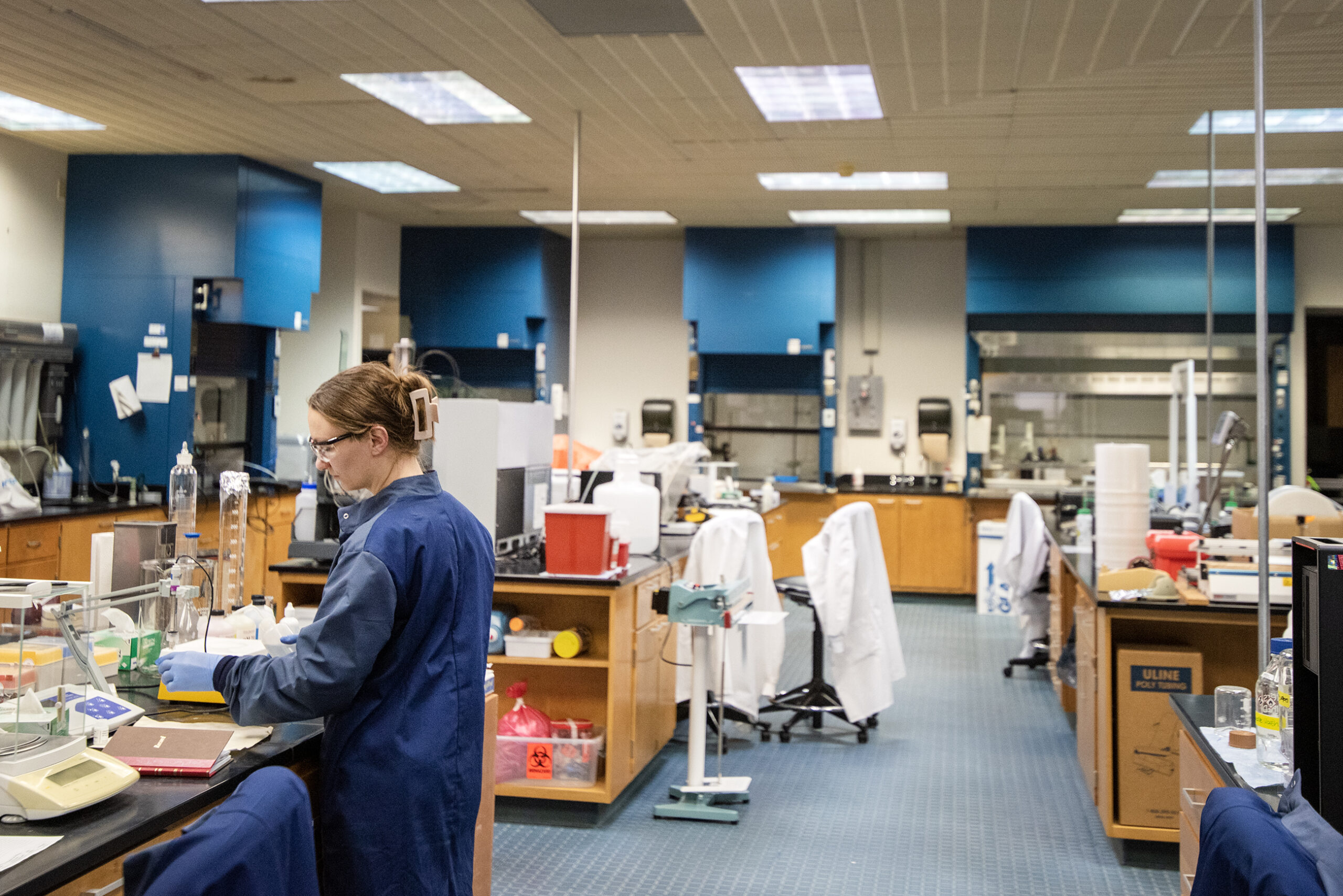 A woman in a blue lab coat works in a lab.