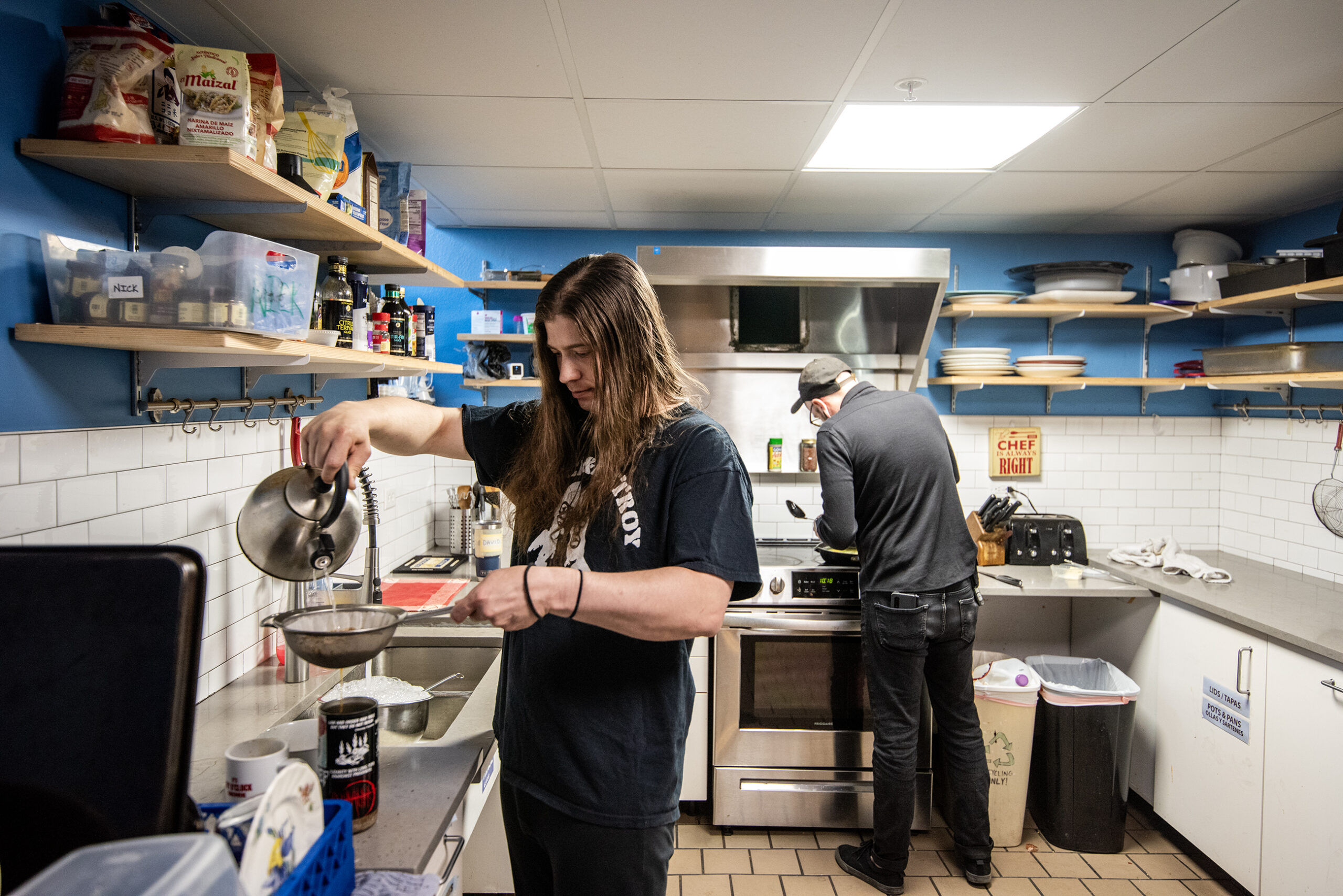 A resident uses a kettle to pour hot water over coffee grounds in a kitchen.