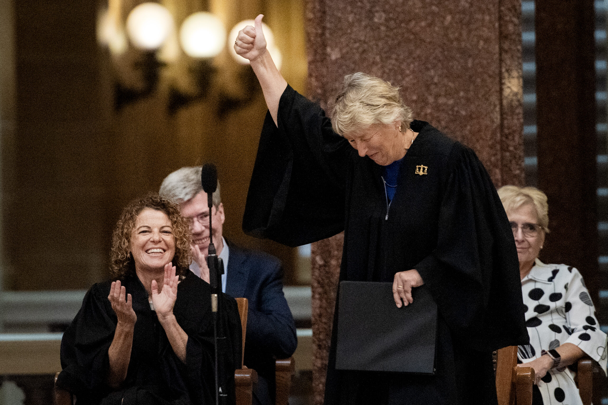 Ann Walsh Bradley raises her hand in the air and gives a thumbs up.